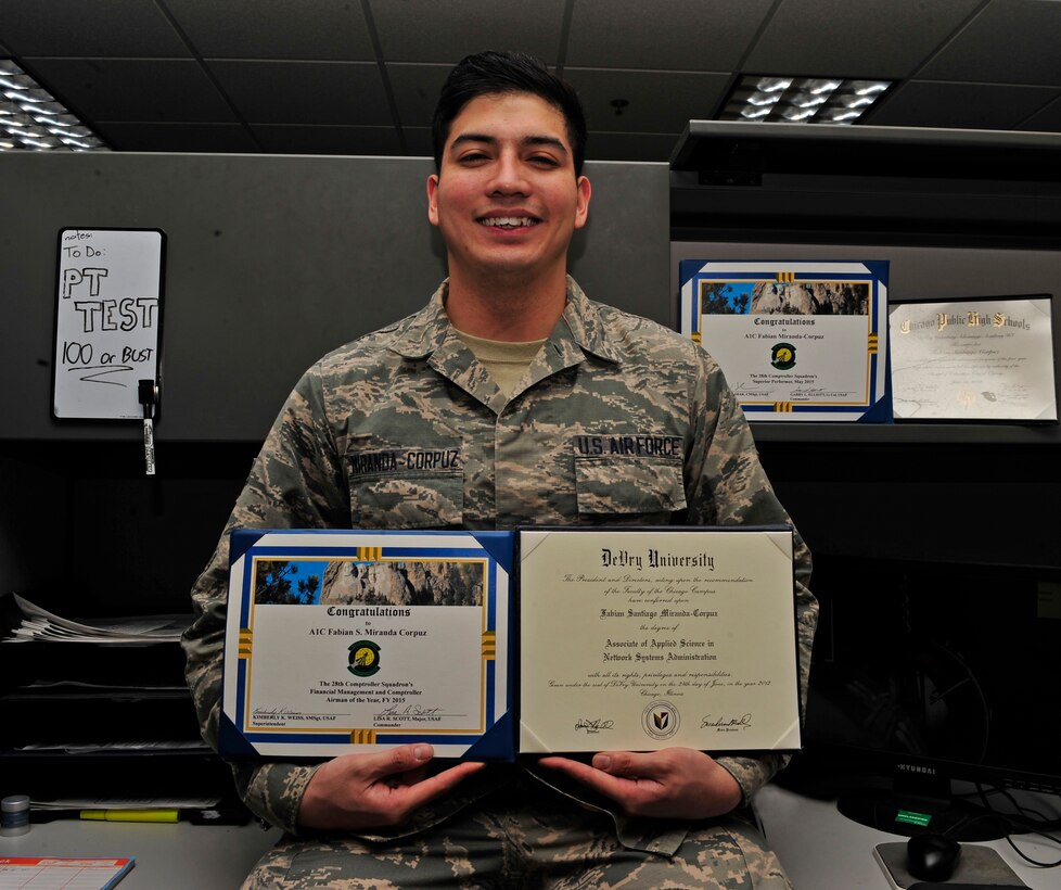 Airman 1st Class Fabian Miranda-Corpuz, 28th Comptroller Squadron budget analyst, sits at his desk with some certificates that helped build his package for acceptance into the Airman Scholarship and Commissioning Program at Ellsworth Air Force Base, S.D., Feb. 22, 2016. Miranda-Corpuz is using the program to pursue his dreams of working for a space program, a dream he has had since childhood. (U.S. Air Force photo by Airman 1st Class James L. Miller/Released)