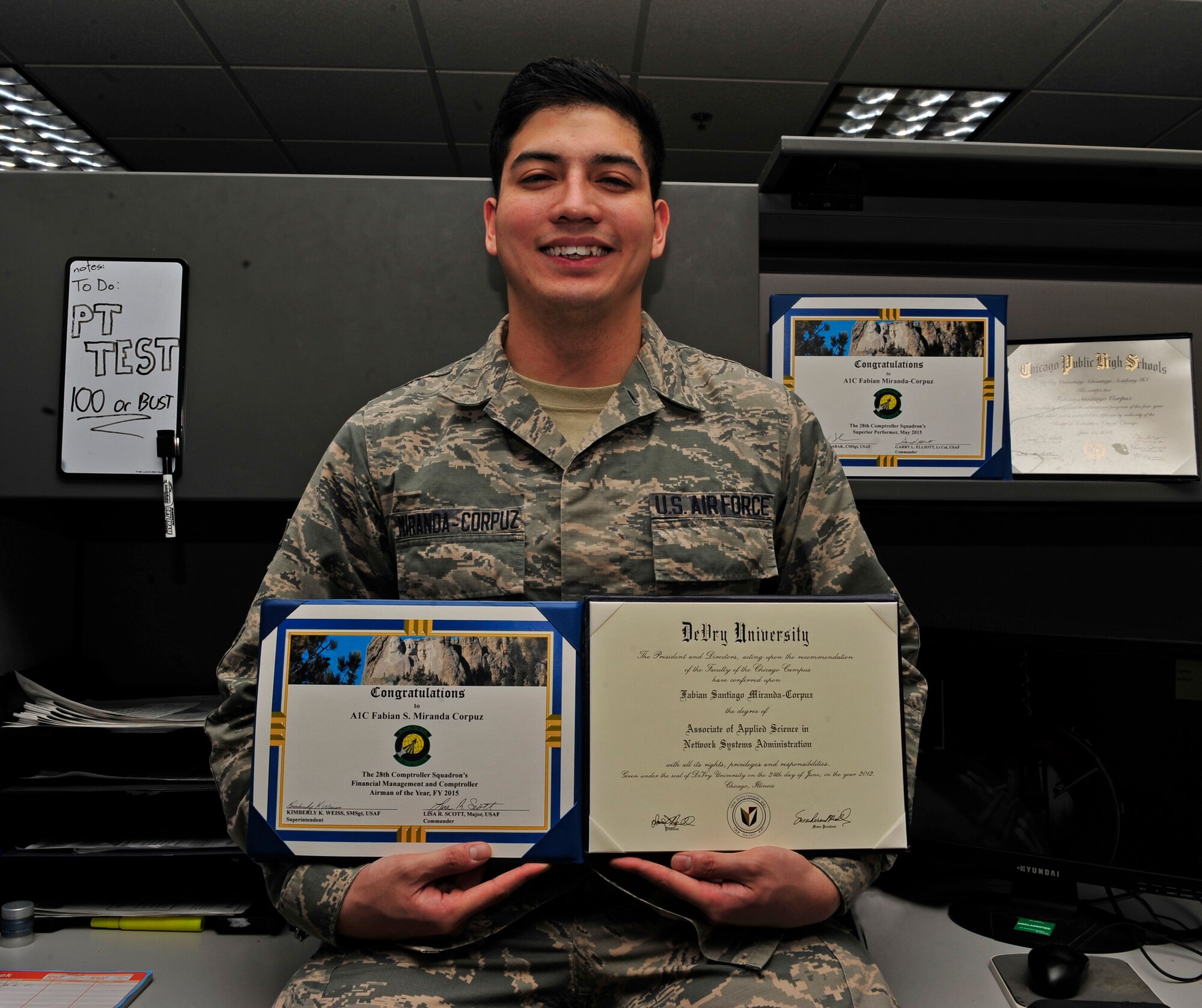 Airman 1st Class Fabian Miranda-Corpuz, 28th Comptroller Squadron budget analyst, sits at his desk with some certificates that helped build his package for acceptance into the Airman Scholarship and Commissioning Program at Ellsworth Air Force Base, S.D., Feb. 22, 2016. Miranda-Corpuz is using the program to pursue his dreams of working for a space program, a dream he has had since childhood. (U.S. Air Force photo by Airman 1st Class James L. Miller/Released)