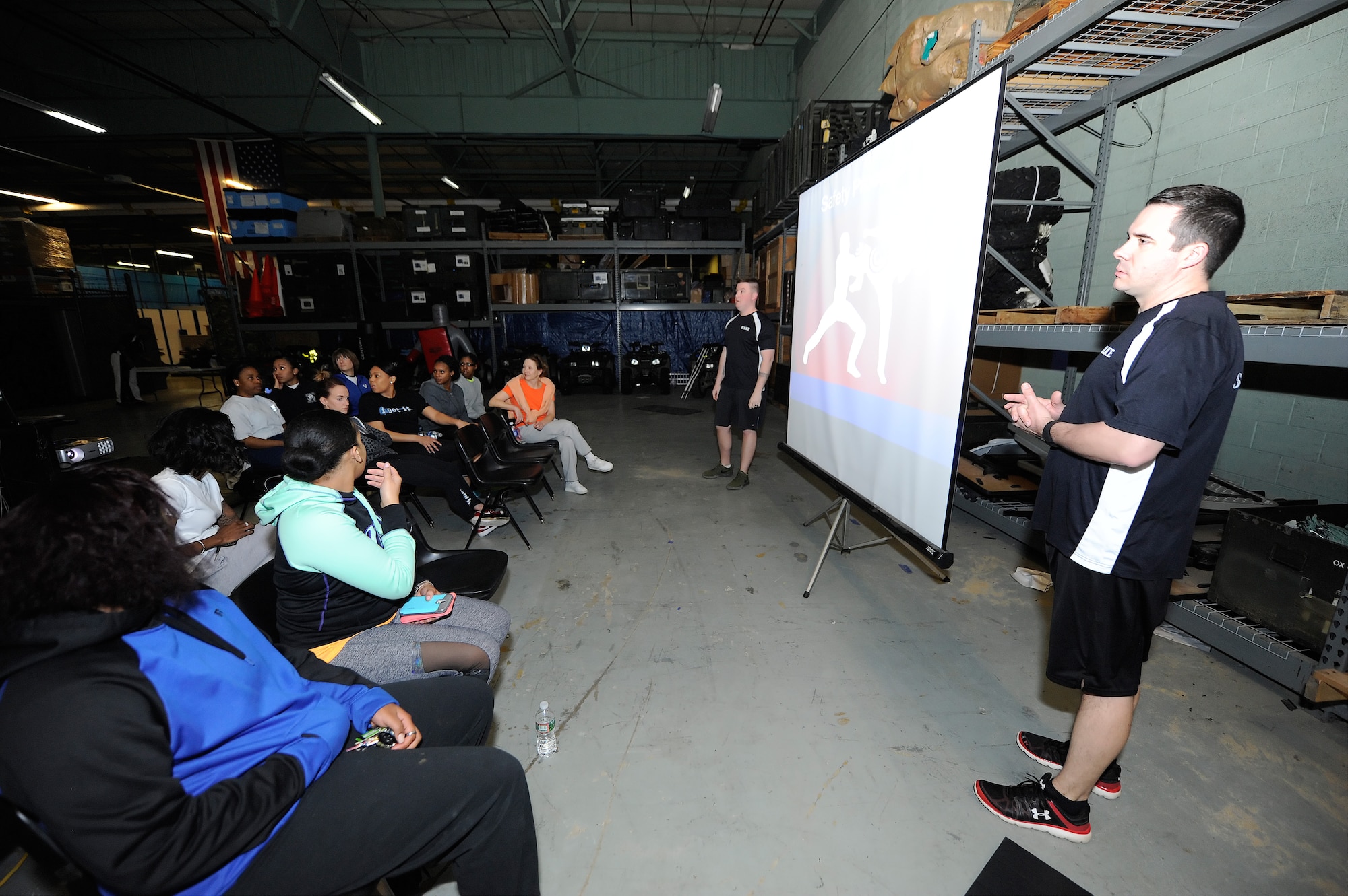 Tech. Sgt. Michael Johnson, right, 436th Security Forces Squadron, NCO in charge of training, and Staff Sgt. Bryan Miller, 436th SFS patrolman, discuss self-defense moves with a gathered audience of women during the Safety and Self-Defense Strategy program Feb. 26, 2016, at Dover Air Force Base, Del. The course provided safety tips and self-defense training to military and dependent women inside the SFS training facility. (U.S. Air Force photo/Greg L. Davis)