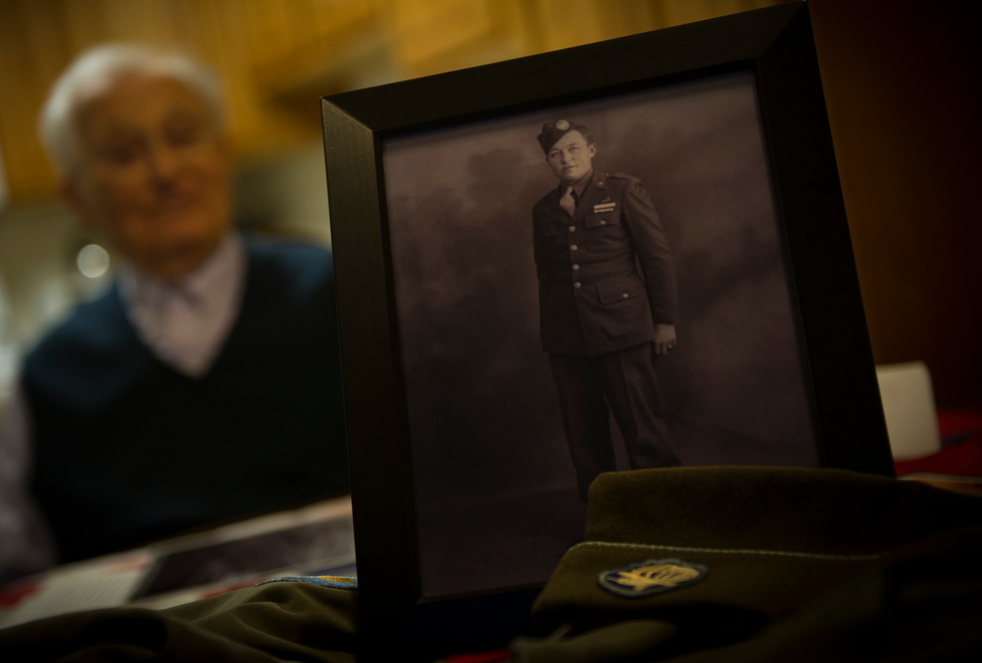 U.S. Army Private 1st Class (Sep.) Lynn Aas, 17th Airborne Division combat infantry rifleman, looks at a photo of himself from 1944 in his home in Minot, N.D., Feb. 18, 2016. Aas was considered a paratrooper, as his unit would fly into their combat destinations on gliders. (U.S. Air Force photo/Senior Airman Apryl Hall)
