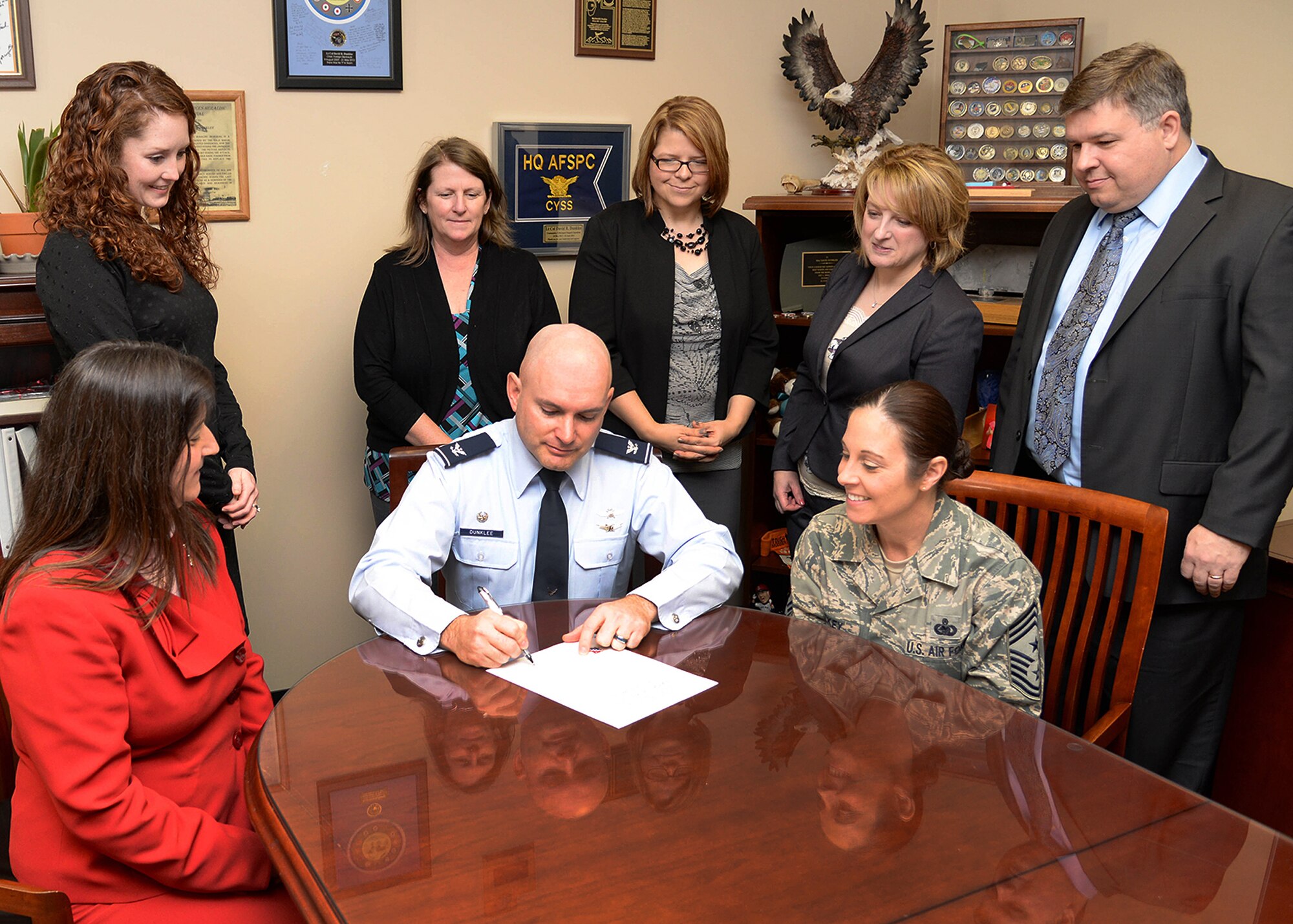 Col. David R. Dunklee, 66th Air Base Group commander, signs a Women's History Month proclamation in his office Feb. 29 while Tom Fredericks, right, 66 ABG deputy commander, Command Chief Master Sgt. Patricia L. Hickey, seated right, Barbara Briand, seated left, WHM committee chair, and other committee members look on. The theme for this year's WHM campaign is Honoring Women in Public Service. (U.S. Air Force photo by Linda LaBonte Britt)