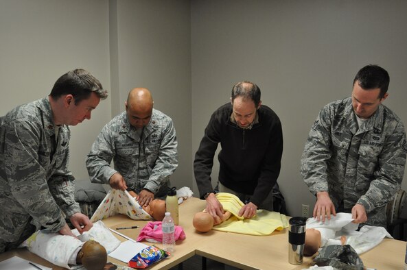 Participants in Dads 101, practice swaddling, a technique designed to keep babies warm. The Feb. 29 class focused on providing soon-to-be dads and current fathers with basic skills and tips to successful parenting. (U.S. Air Force photo/Brian Brackens)
