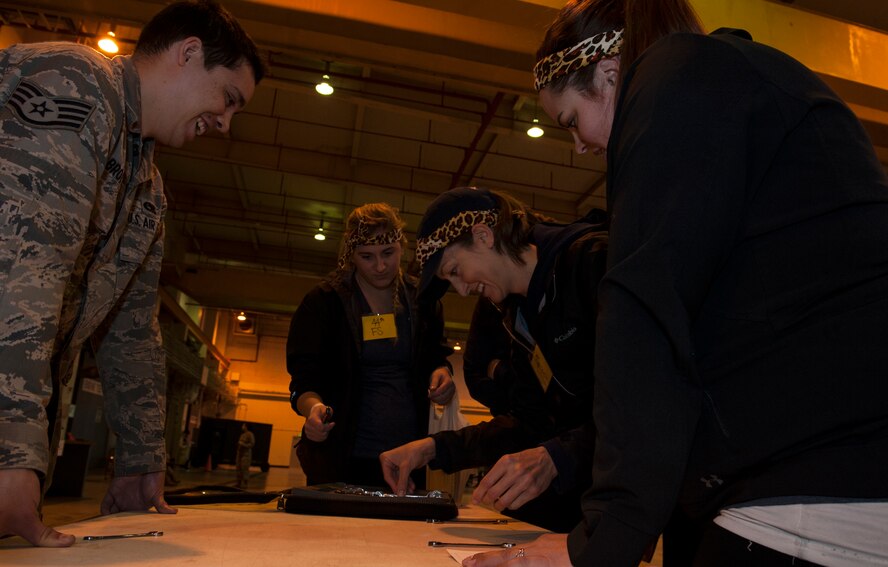 U.S. Air Force Staff Sgt. Kyle Brotherton, 18th Component Maintenance Squadron F-15 Eagle crew chief, assists spouses from the 44th Fighter Squadron with a challenge during Team Kadena Spouses’ Amazing Race Feb. 24, 2016, at Kadena Air Base, Japan. During this particular challenge, team members had to arrange a set of tools correctly and find a tool that was incorrectly labeled. (U.S. Air Force photo by Airman 1st Class Lynette M. Rolen)