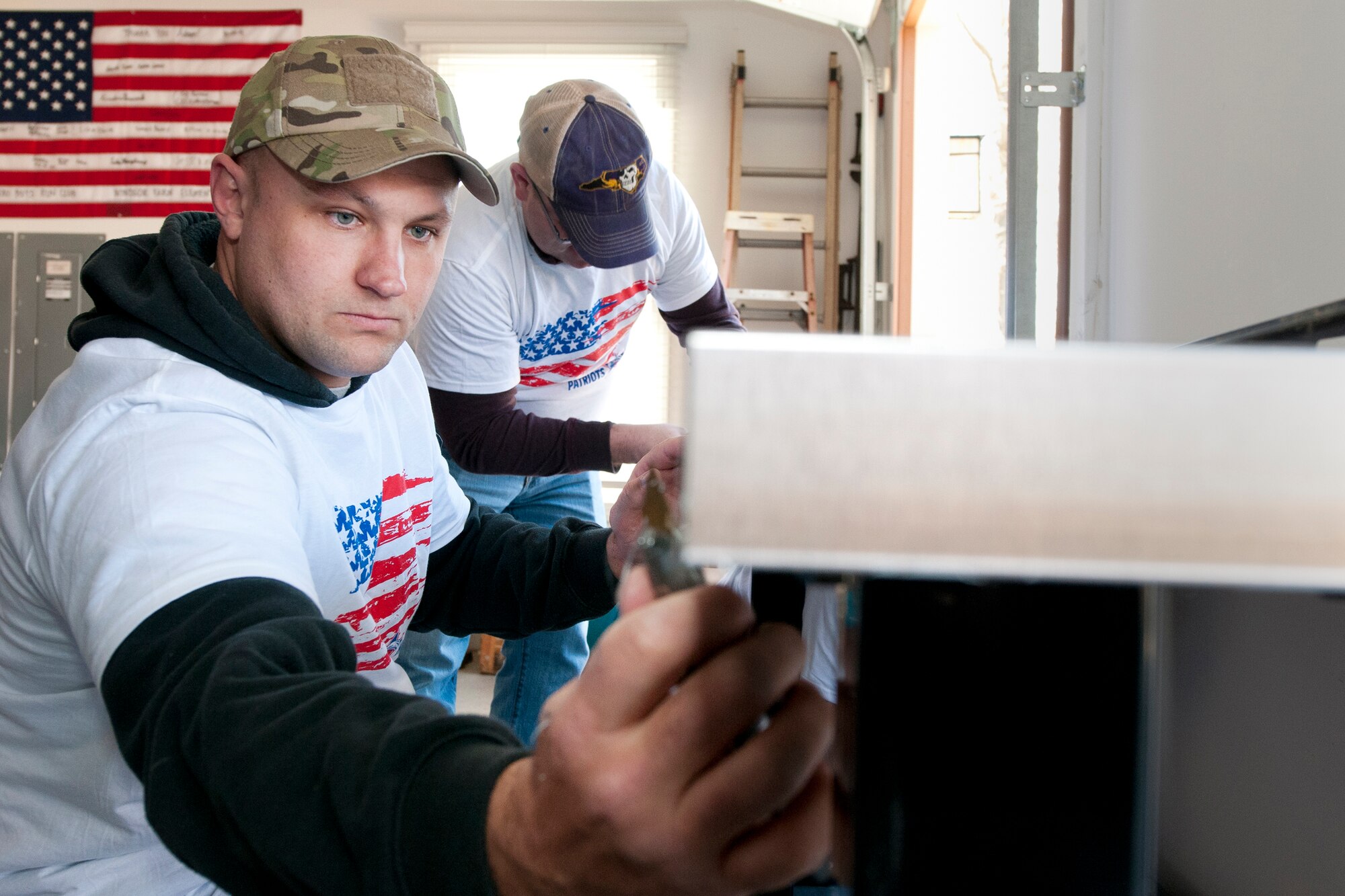 Master Sgt. Steve Simkonis, 459th Aircraft Maintenance Squadron crew chief, uses a knife to remove a protective plastic seal from the surface of a workbench installed in the garage of U.S. Army Sgt. (ret.) Adam Keys’ home in Annapolis, Md., Feb. 27, 2016. Ten members of the 459 AMXS volunteered on behalf of the nonprofit Patriots Honor to unpack, build and install workbenches, power tools and roll-aways in Keys’ garage in an effort to help make dreams come true for Wounded Warriors. Keys, a triple amputee who has endured more than 130 surgeries due to injuries sustained from an IED explosion in Afghanistan in 2010, intends to use the equipment to pursue his hobby of building small engines and model cars. (U.S. Air Force photo by Staff Sgt. Kat Justen)