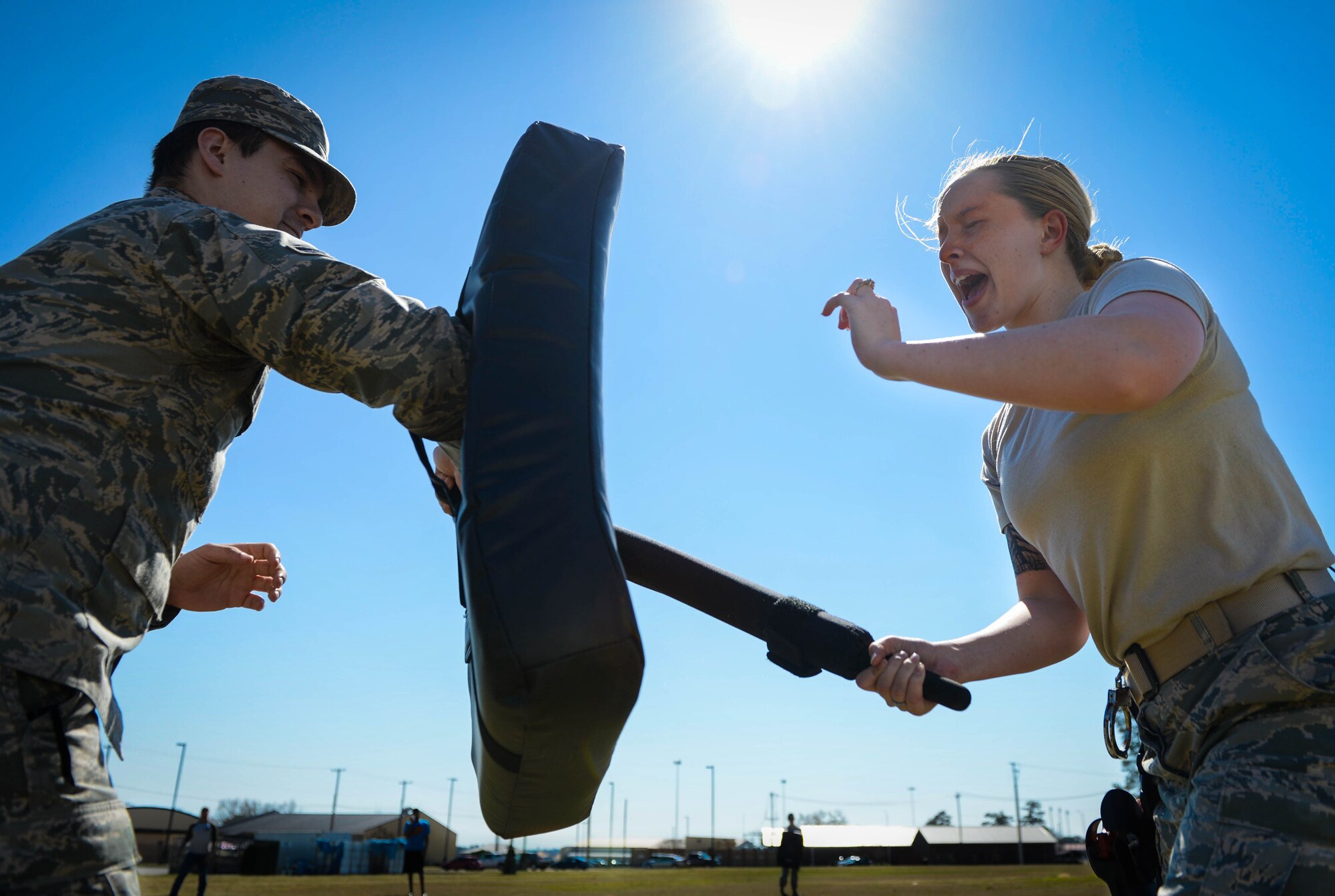 U.S. Air Force Airman 1st Class Hannah McCoy, 20th Security Forces Squadron journeyman (right), reacts to pepper spray while hitting a simulated perpetrator during training at Shaw Air Force Base, S.C., Feb. 29, 2016. McCoy, new to the 20th SFS, participated in the training to understand the effects of pepper spray. (U.S. Air Force photo by Senior Airman Jensen Stidham) 