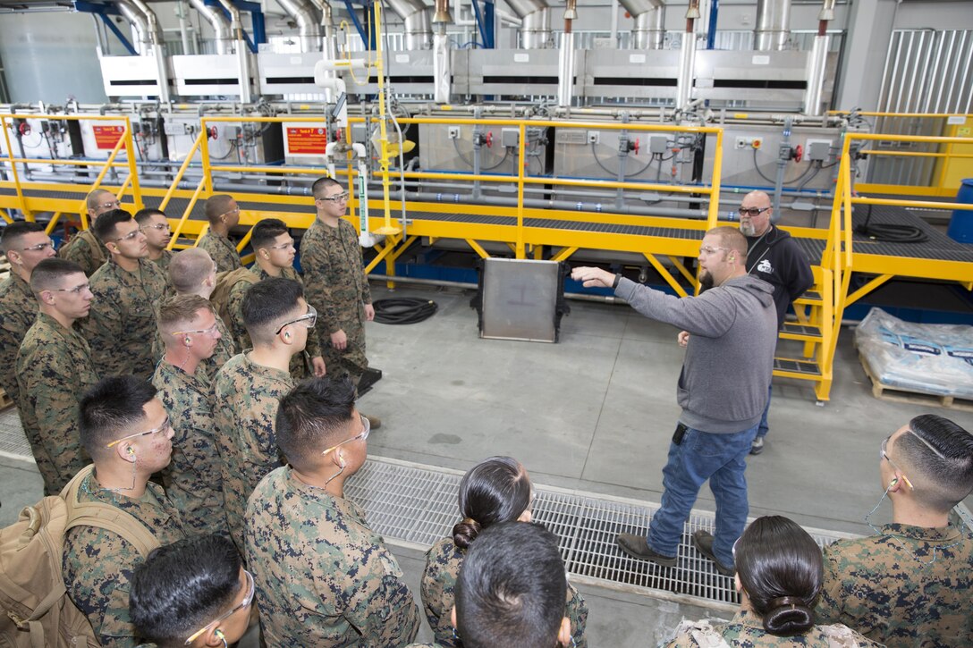 Chris Ware, sand blast supervisor aboard Marine Corps Logistics Base, Production Plant Barstow, guides Combat Logistics Battalion-453 Marines on a tour of the plant's coating facility Feb 19. The CLB Marines spent the day aboard Marine Corps Logistics Base Barstow learning about the maintenance operations carried out at PPB and received a period of military instruction on rail operations.