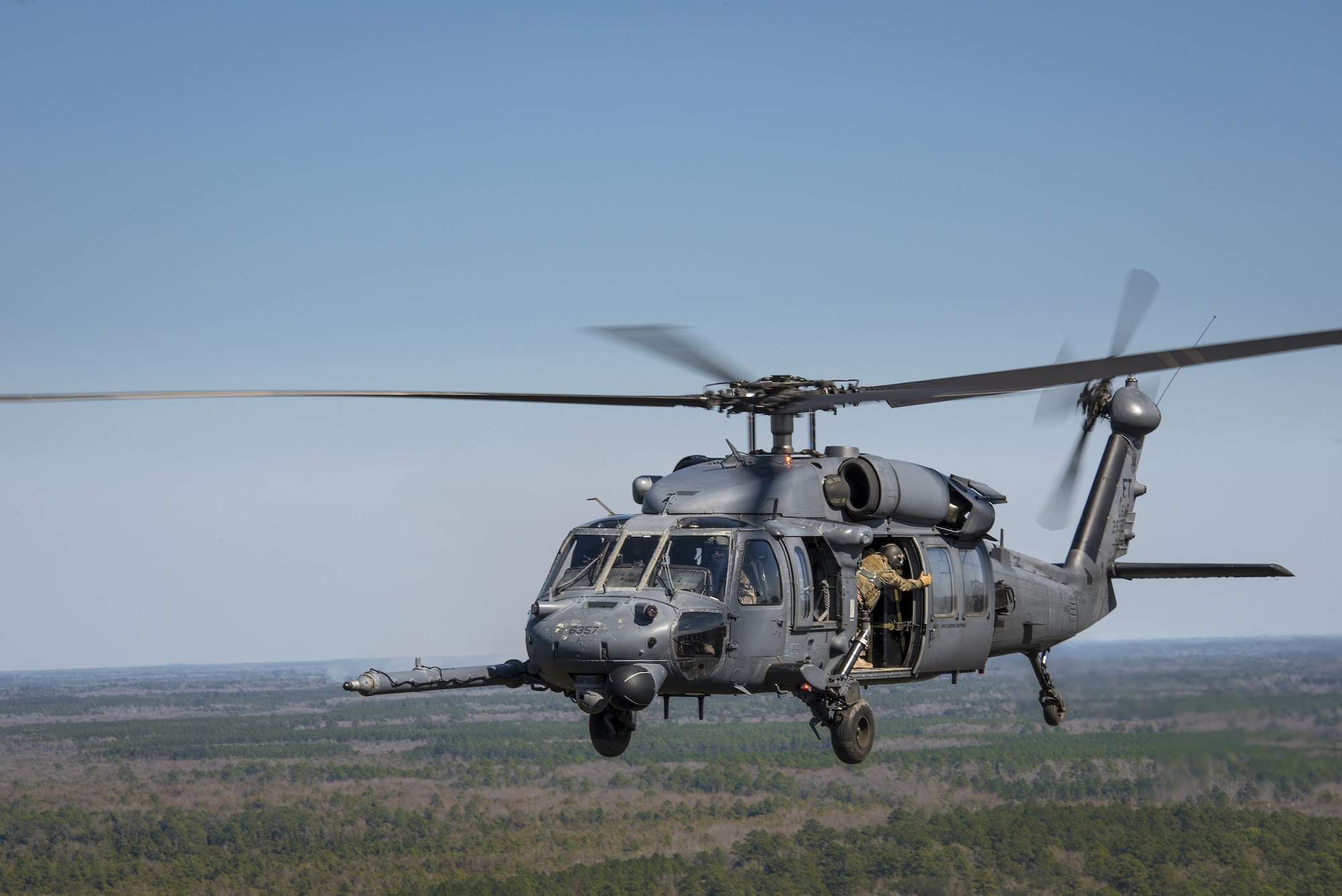 A special missions aviator from the 41st Rescue Squadron closes the door on an HH-60G Pave Hawk, Feb. 11, 2016, in the skies over Moody Air Force Base, Ga.  Multiple U.S. Air Force aircraft within Air Combat Command conducted joint aerial training at Grand Bay Bombing and Gunnery Range. During the training, the aircraft conducted tactical air and ground maneuvers, as well as weapons training. (U.S. Air Force photo by Senior Airman Ryan Callaghan/Released)