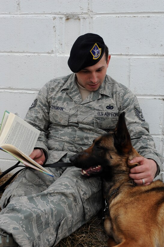 A military working dog handler from the 28th Security Forces Squadron reads to his partner. Images were captured of Airmen reading around the base in recognition of National Read Across America Day, an observance in the United States celebrated on the school day closest to March 2, the birthday of Dr. Seuss. This day is a part of an overall Read Across America initiative, created by the National Education Association, dedicated to reading. (U.S. Air Force photo by Senior Airman Hailey Staker)