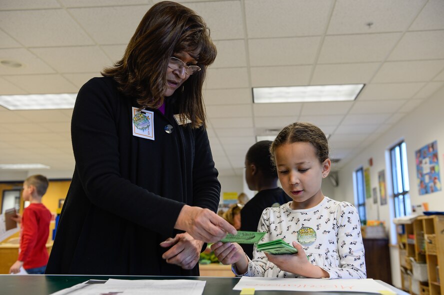 Liz Archuleta, Airman Family and Readiness Center, assists Zoe Allen paying for bills during “The Game of Life” Friday, Feb. 26, 2016, in the Child Development Center at Schriever Air Force Base, Colorado. The game was designed to help children learn about the importance of saving money as part of Military Saves Week. (U.S. Air Force photo/Christopher DeWitt)