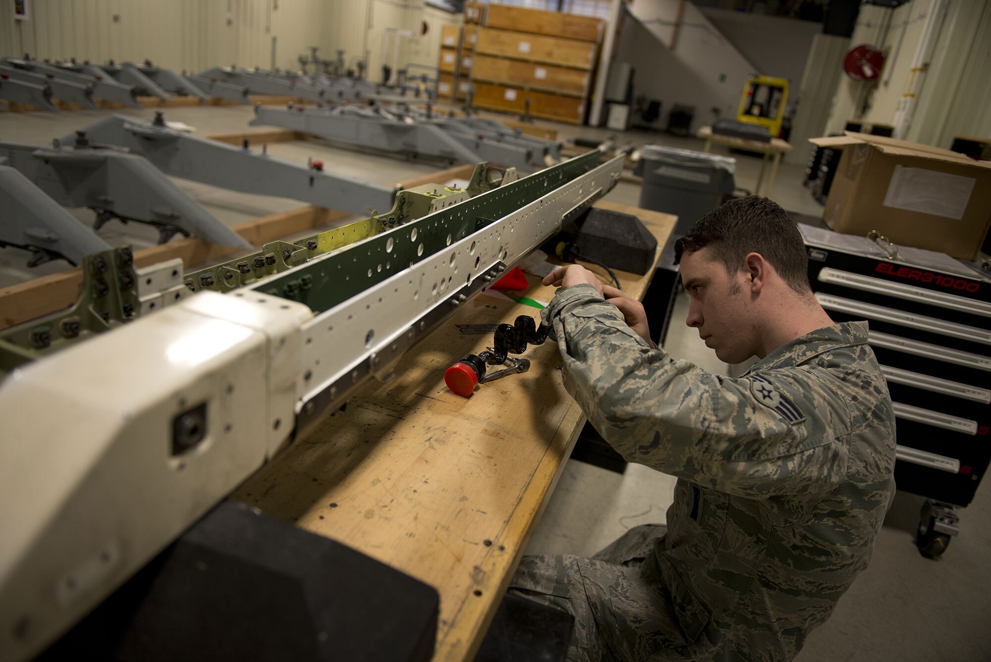 Senior Airman Dominic Hobbs, a 3rd Aircraft Maintenance Squadron weapons load crew member, works on a key part needed to equip the Air Intercept Missile-9X to an F-22 Raptor March 1. Each part originally took a week to complete, but by consolidating the 525th Aircraft Maintenance Unit, 90th Aircraft Maintenance Unit, and 3rd Munitions Squadron’s Armament flight into one temporary location, they have been able to reduce that time to 72 hours and complete enough rails ahead of schedule to allow for the first F-22 Raptor sortie with an AIM-9X to be flown March 1.0 (U.S. Air Force photo by Airman 1st Class Kyle Johnson)