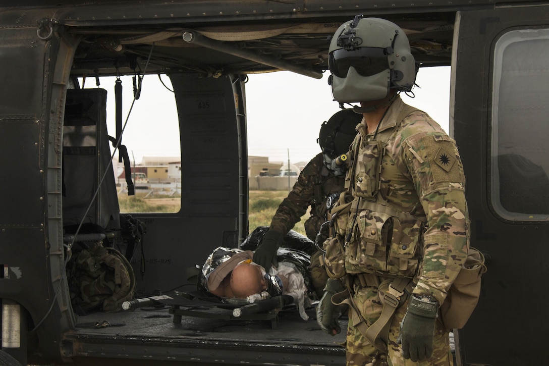 Army Sgt. Lopez, foreground, stands by to help soldiers load a simulated casualty for evacuation on a UH-60 Black Hawk helicopter at a tactical combat casualty care lane at Camp Buehring, Kuwait, Feb. 23, 2016. Lopez is a crew chief assigned to Company F, 2nd Battalion, 238th Aviation Regiment, 40th Combat Aviation Brigade. Army photo by Staff Sgt. Ian M. Kummer