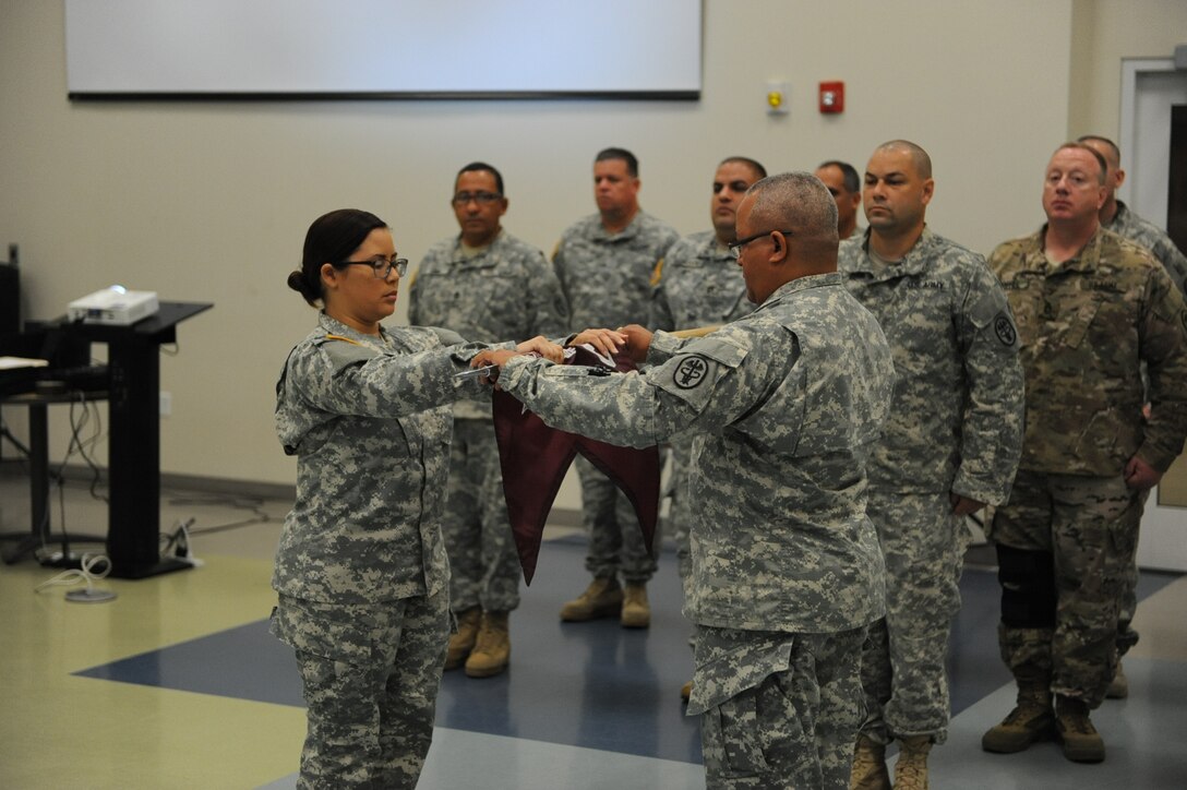 Capt. Yomaris Rivera and 1st Sgt. roll the Community Care Unit Flag prior to casing it and finalizing the inaction of the unit, during a ceremony on Fort Buchanan, PR, March 1. (Photo by US Army Spc. Anthony Martinez)