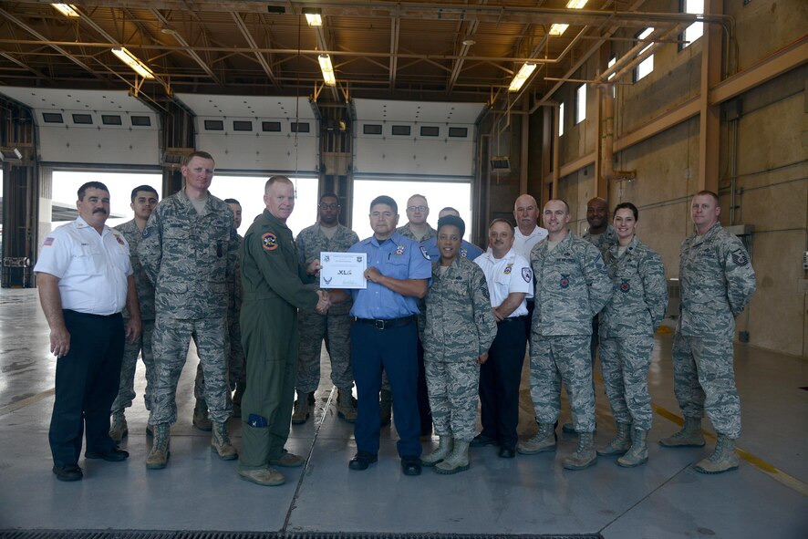 Raul Castorena, center, 47th Civil Engineer Squadron firefighter, accepts the “XLer of the Week” award from Col. Darrell Judy, left, 47th Flying Training Wing vice commander, and Chief Master Sgt. Erica Shipp, right, 47th Mission Support Group superintendent, here, March 1, 2016. The XLer is a weekly award chosen by wing leadership and is presented to those who consistently make outstanding contributions to their unit and Laughlin. (U.S. Air Force photo by Airman 1st Class Brandon May)