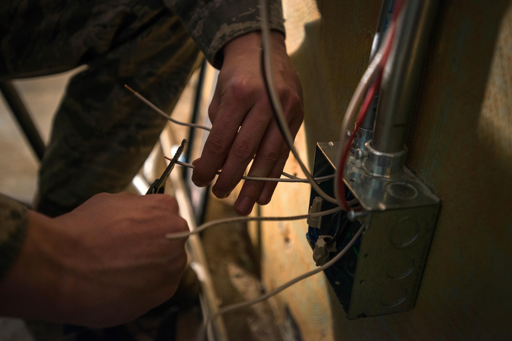 Airman 1st Class Joshua Sprinkles, a 354th Civil Engineer Squadron electrical technician, is shadowed by work lights while he roughs in wires during a remodel in Amber Hall on March 3, 2016, at Eielson Air Force Base, Alaska. With the lights off deep in the basement, the wiring is the ground work that will power office space to support missions across the U.S. Pacific Air Forces area of responsibility. (U.S. Air Force photo by Staff Sgt. Shawn Nickel/Released) 