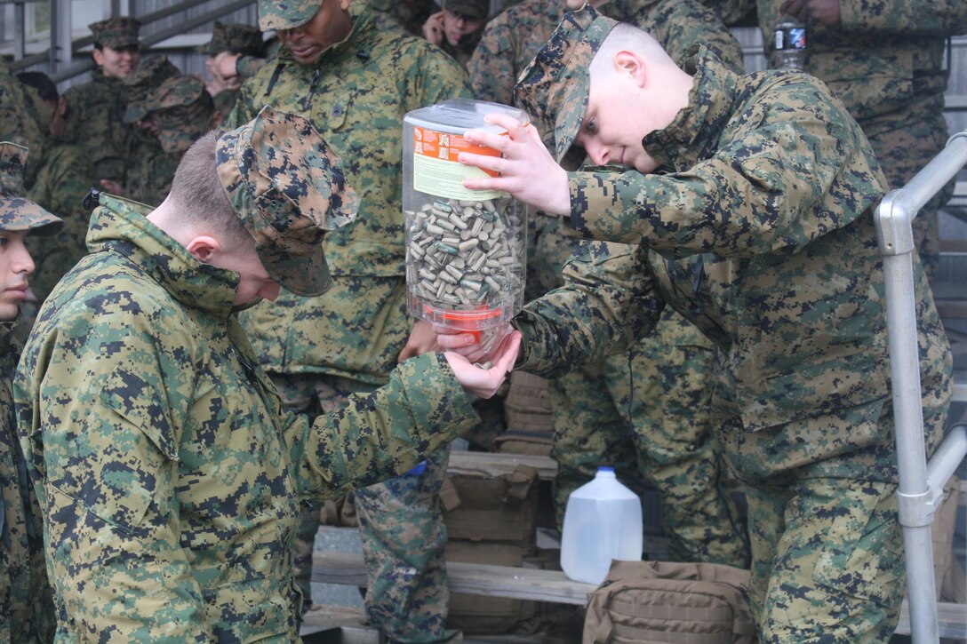 Marines with Headquarters and Service Battalion receive ear protection prior to a weapons familiarization live fire event.