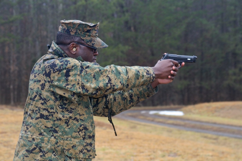 A Marine with Headquarters and Service Battalion fires a pistol.