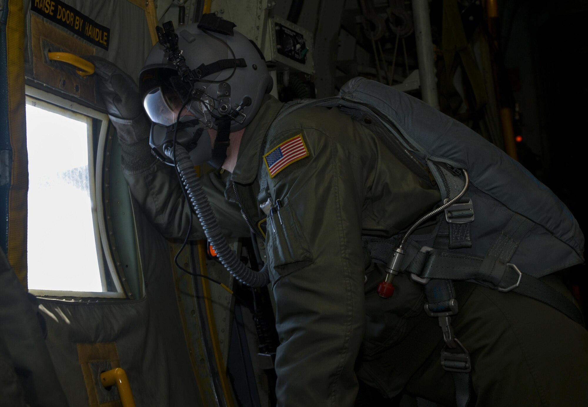 Senior Airman Christopher Hofer, 36th Airlift Squadron loadmaster, looks out a window of a C-130 Hercules while in flight over Yokota Air Base, Japan, March 2, 2016. Members of the 374th Operations Support Squadron survival, evasion, resistance and escape flight performed static line and high-altitude, low-opening jumps in order to maintain their qualifications. (U.S. Air Force photo by Senior Airman David Owsianka/Released)