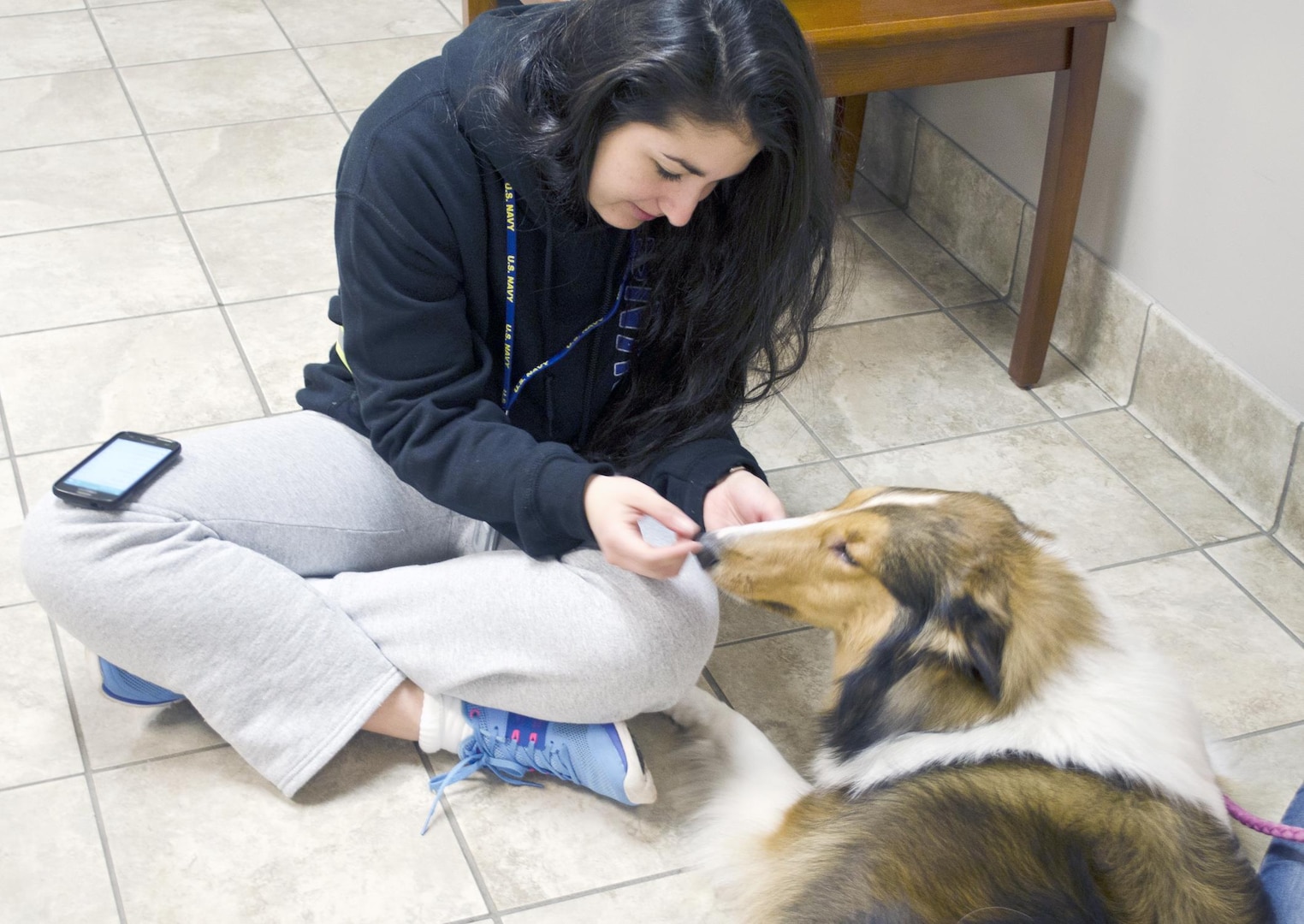 Seaman Jeniffer Rodriguez, a student in the Basic Medical Technician Corpsman Program at the Medical Education and Training Campus on Joint Base San Antonio-Fort Sam Houston, pets Lady, one of the Navy Chaplain Lt. Cmdr. Scott Adams’ certified therapy dogs, during “Pet Therapy” night at the Navy student barracks.