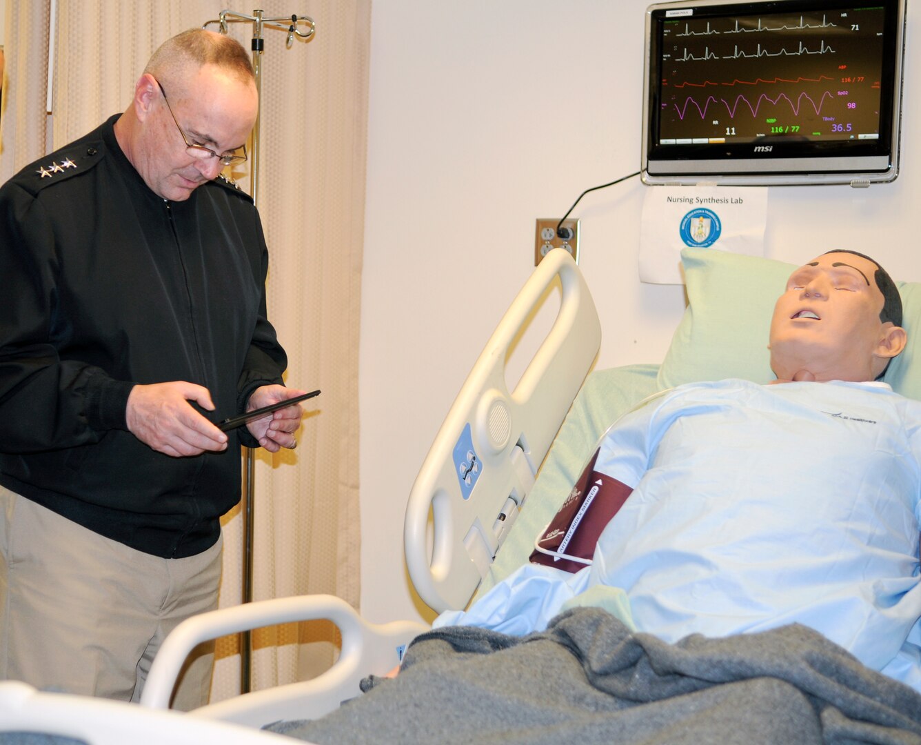 SAN ANTONIO (Feb. 19, 2016) Vice Adm. C. Forrest Faison III, Navy Surgeon General and Chief, Bureau of Medicine and Surgery (BUMED), uses a tablet to control a simulation model in the nursing synthesis lab at the Medical Education and Training Campus on board Joint Base San Antonio - Fort Sam Houston, Texas. The lab is a part of the Basic Medical Technician Corpsman Program where all hospital corpsmen students get hands-on experience with simulated patients. (U.S. Navy photo by Mass Communication Specialist 1st Class Jacquelyn D. Childs/Released)