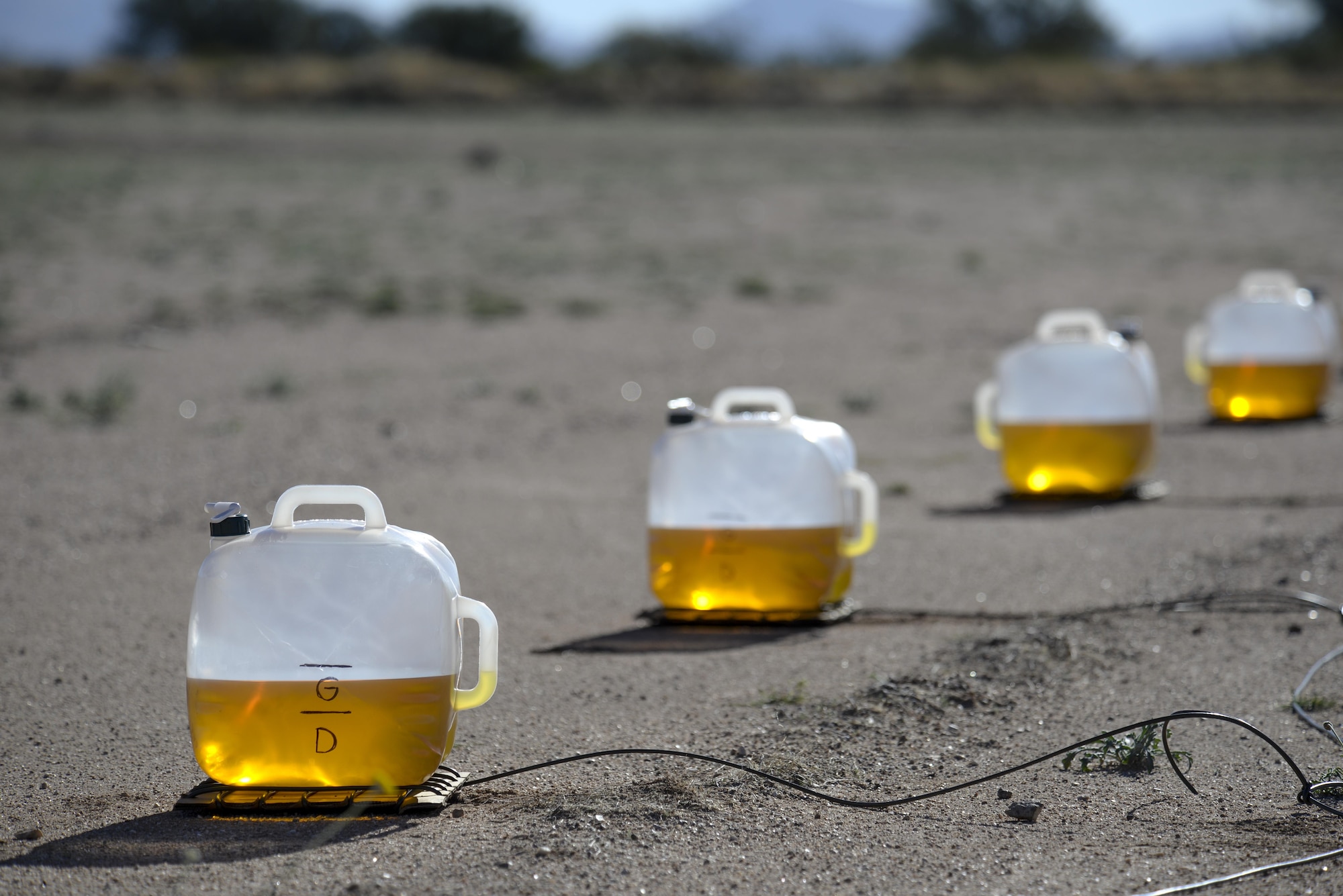 Containers prepared by 355th Civil Engineer Squadron explosive ordnance technicians are filled with a mixture of gasoline and diesel prior to detonation  at Davis-Monthan Air Force Base, Ariz., Feb. 18, 2016. The EOD flight practiced for the pyrotechnic demonstration they will display at the upcoming 2016 Thunder and Lighting over Arizona open house.  (U.S. Air Force photo by Senior Airman Chris Massey/Released)