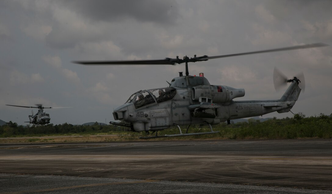 A AH-1 Cobra (Right) and a UH-1Y Huey prepare to touch down at a refuel point before a flight mission during exercise Cobra Gold 16 in Utapao, Thailand, Feb. 16, 2016. The Huey and Cobra usually fly together to increase mission capabilities. The Huey brings capable sensors and the Cobra brings long distance weapon systems resulting in a reliable escort team. The Marines are with Marine Light Attack Helicopter Squadron 167, currently supporting Marine Aircraft Group 36, 1stl Marine Aircraft Wing, III Marine Expeditionary Force as part of the unit deployment program. (U.S. Marine Corps photo by Cpl. William Hester/ Released)