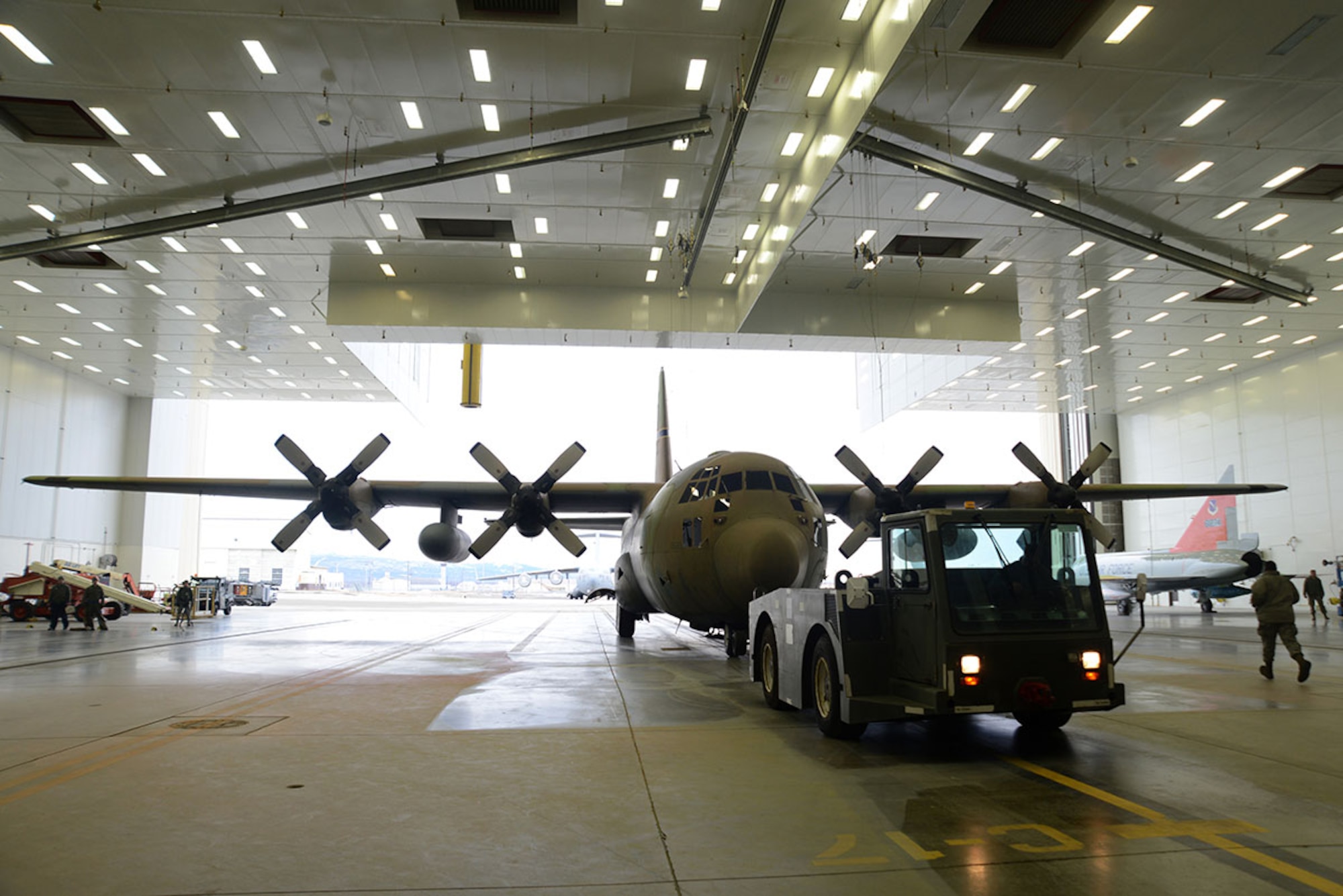 Airmen and contracted personnel work together to tow the static C-130 Hercules into Hangar 21 at Joint Base Elmendorf-Richardson Feb. 27, 2016. The aircraft has been towed to Hangar 21 for refurbishment and is scheduled to return to Heritage Park in April. (U.S. Air Force photo by Airman 1st Class Christopher R. Morales)