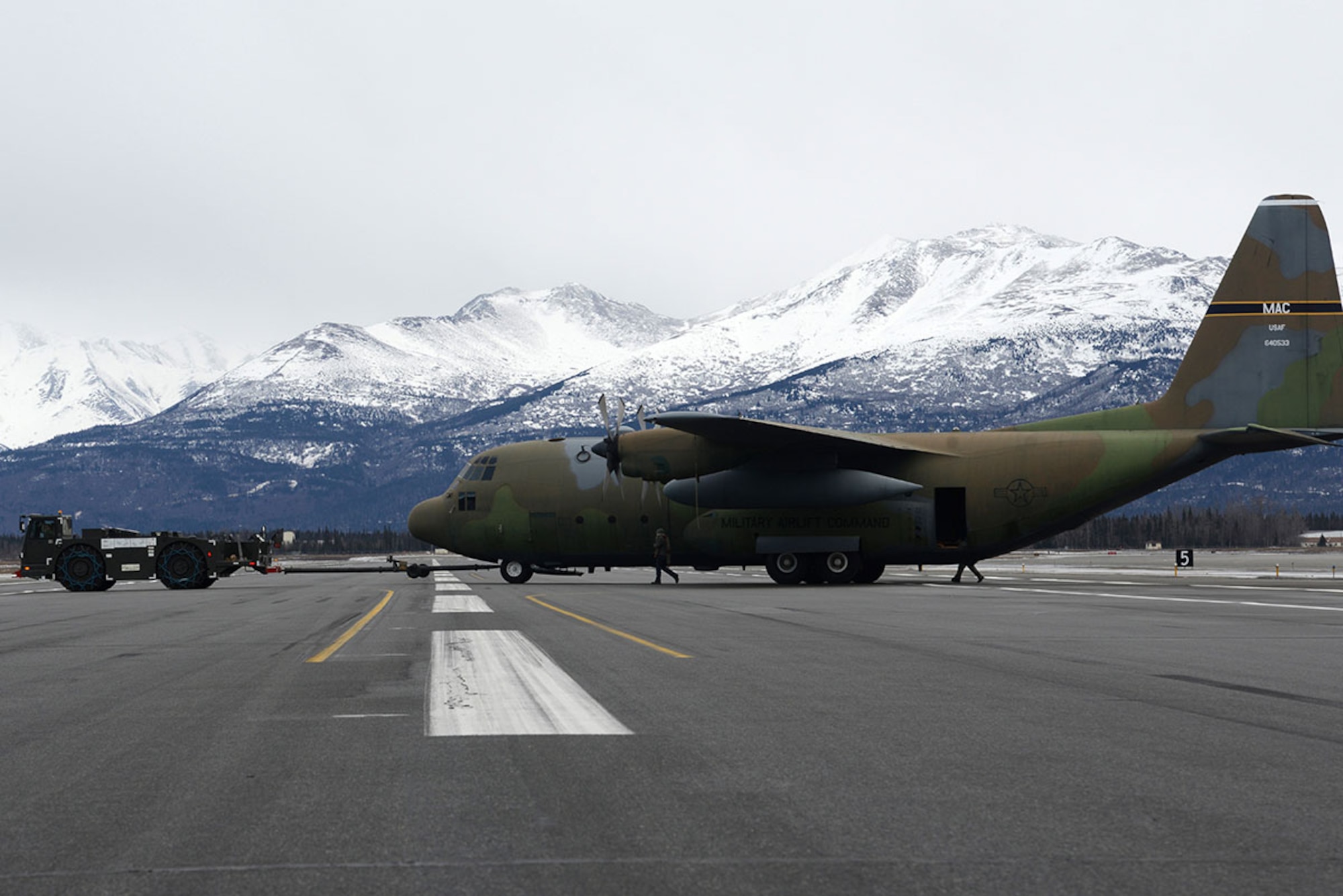 Airmen and contracted personnel work together to tow the static C-130 Hercules across the flight line at Joint Base Elmendorf-Richardson Feb. 27, 2016. The aircraft has been towed to Hangar 21 for refurbishment and is scheduled to return to Heritage Park in April. (U.S. Air Force photo by Airman 1st Class Christopher R. Morales)