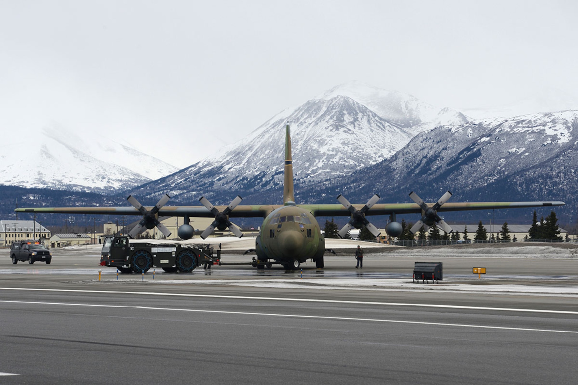 Airmen and contracted personnel work together to tow the static C-130 Hercules across the flight line at Joint Base Elmendorf-Richardson Feb. 27, 2016. The aircraft has been towed to Hangar 21 for refurbishment and is scheduled to return to Heritage Park in April. (U.S. Air Force photo by Airman 1st Class Christopher R. Morales)