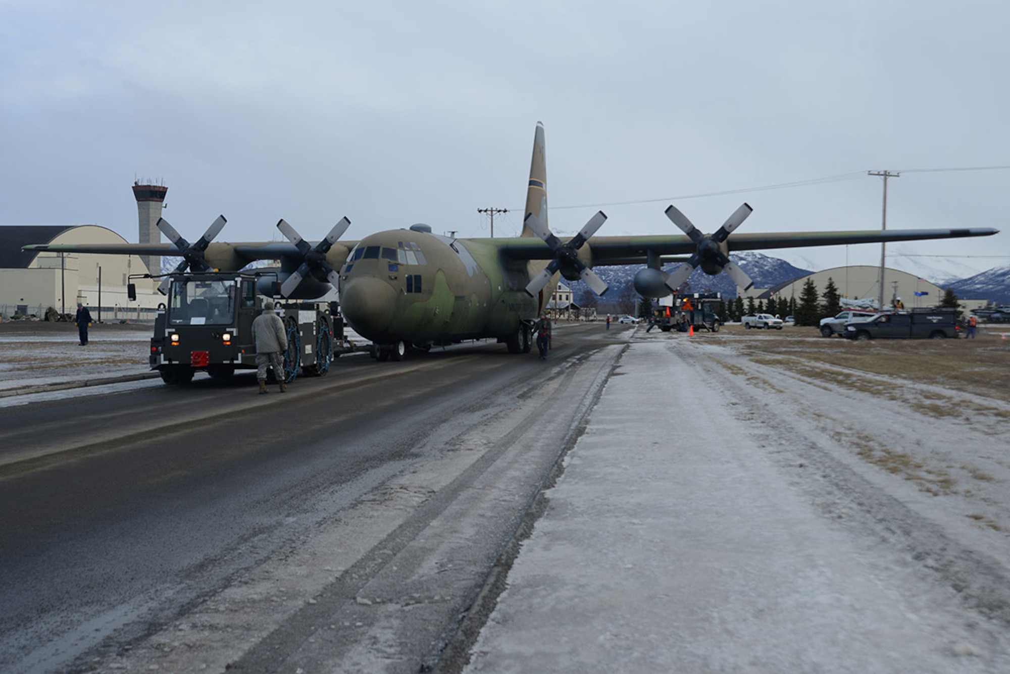 Airmen and contracted personnel work together to tow the static C-130 Hercules at Joint Base Elmendorf-Richardson Feb. 27, 2016. The aircraft has been towed to Hangar 21 for refurbishment and is scheduled to return to Heritage Park in April. (U.S. Air Force photo by Airman 1st Class Christopher R. Morales)