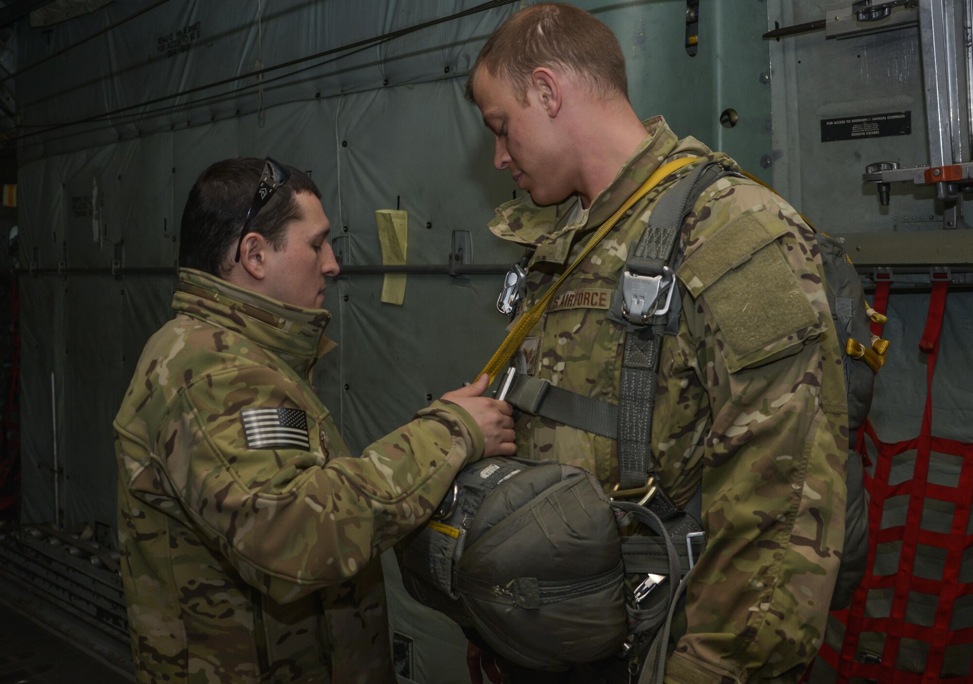 Tech. Sgt. Benjamin Jonas, 374th Operations Support Squadron survival, evasion, resistance and escape operations NCO in charge, performs a pre-jump inspection on Staff Sgt. Justin Bender, 374 OSS SERE training NCO in charge, prior to performing a static line jump at Yokota Air Base, Japan, March 2, 2016. Jonas and Bender performed static line and high altitude, low opening jumps with parachutes in order to maintain their qualifications on different types of jumps. (U.S. Air Force photo by Senior Airman David Owsianka/Released)