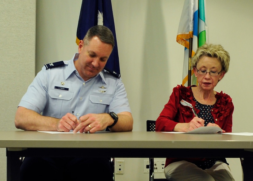 Col. Robert Lyman (left), Joint Base Charleston commander, and Donna Worden (right), Berkley County Library System director, sign an agreement to partner the Berkley County Library with Joint Base Charleston at the Charleston Metro Chamber of Commerce, S.C., March 2, 2016. The agreement allows the BCLS’ bookmobile to supplement the JB Charleston-WS library. (U.S. Air Force photo/Airman Megan E. Munoz)