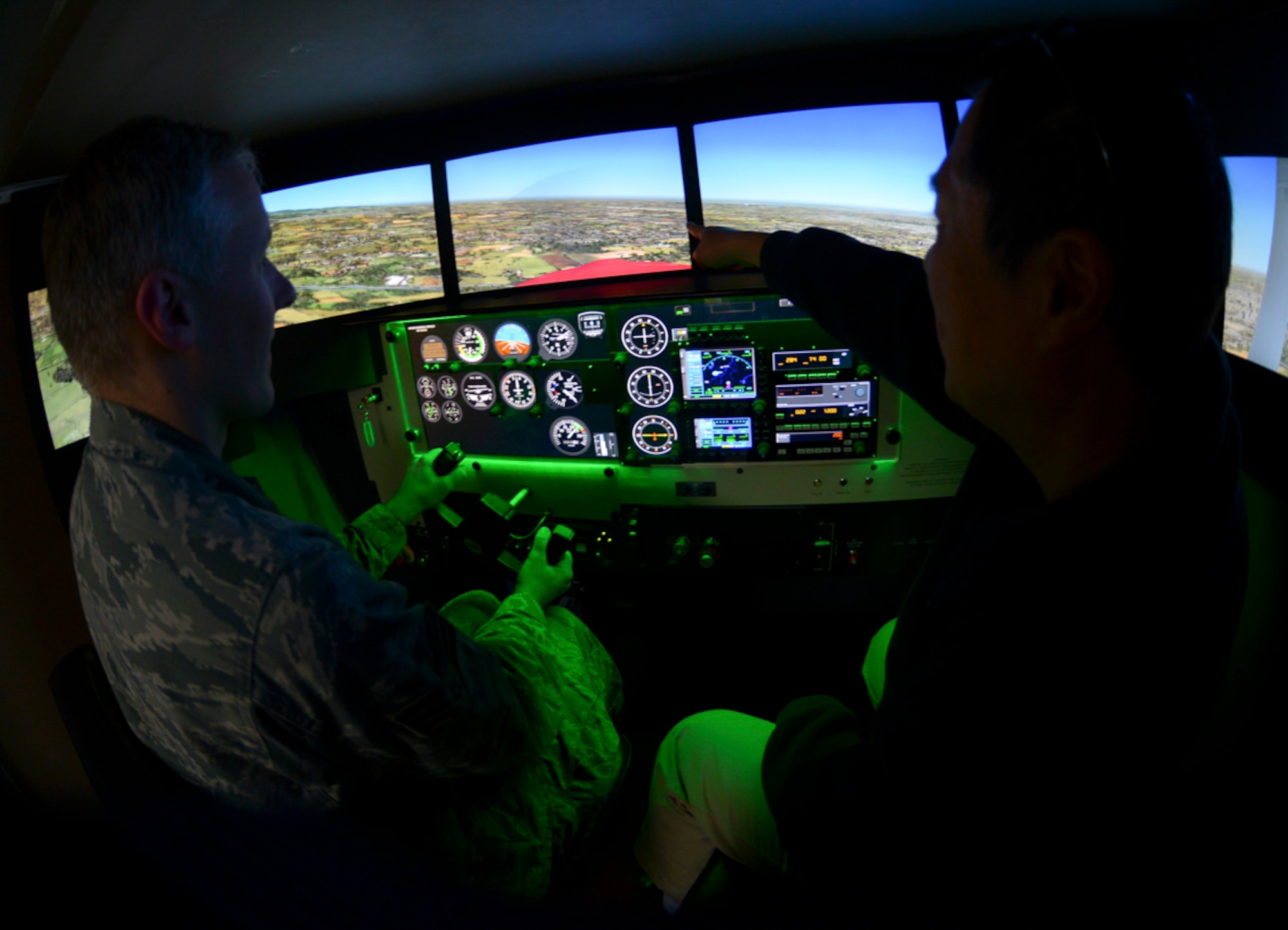 Masayoshi Nakano, Yokota Aero Club and Flight Training Center flight instructor, assists Senior Airman Justin Carnahan, 374th Airlift Wing Public Affairs broadcast journalist, inside the Redbird flight simulator at Yokota Air Base, Japan, Feb. 22, 2015. The flight simulator is designed to mimic the visuals, controls and movement of a Cessna. The aero club makes the simulator available to U.S. military personnel, Japanese citizens with Status of Forces Agreement status and escorted visitors for hourly rental. (U.S. Air Force photo by Airman 1st Class Elizabeth Baker/Released)