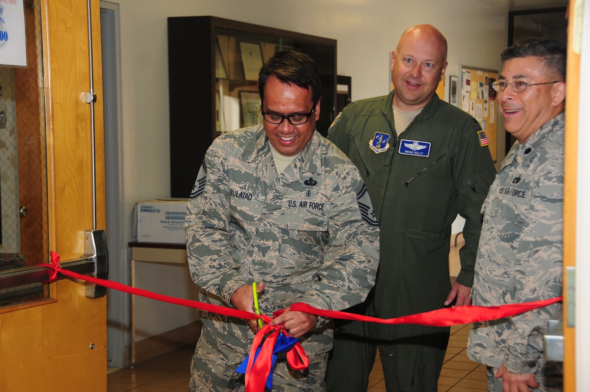 Senior Master Sgt. Neil Bulatao cuts the ribbon for the official re-opening of the 146th Airlift Wing's dining facility alongside Vice Wing Commander Col. Brian Kelly (center) and Force Support Squadron Commander Lt. Col. Abe Quinteros (right). The DFAC has new flooring, furniture and flat screen TVs which all went in after February drill. (U.S. Air National Guard photo by Senior Amn.. Madeleine Richards/Released)