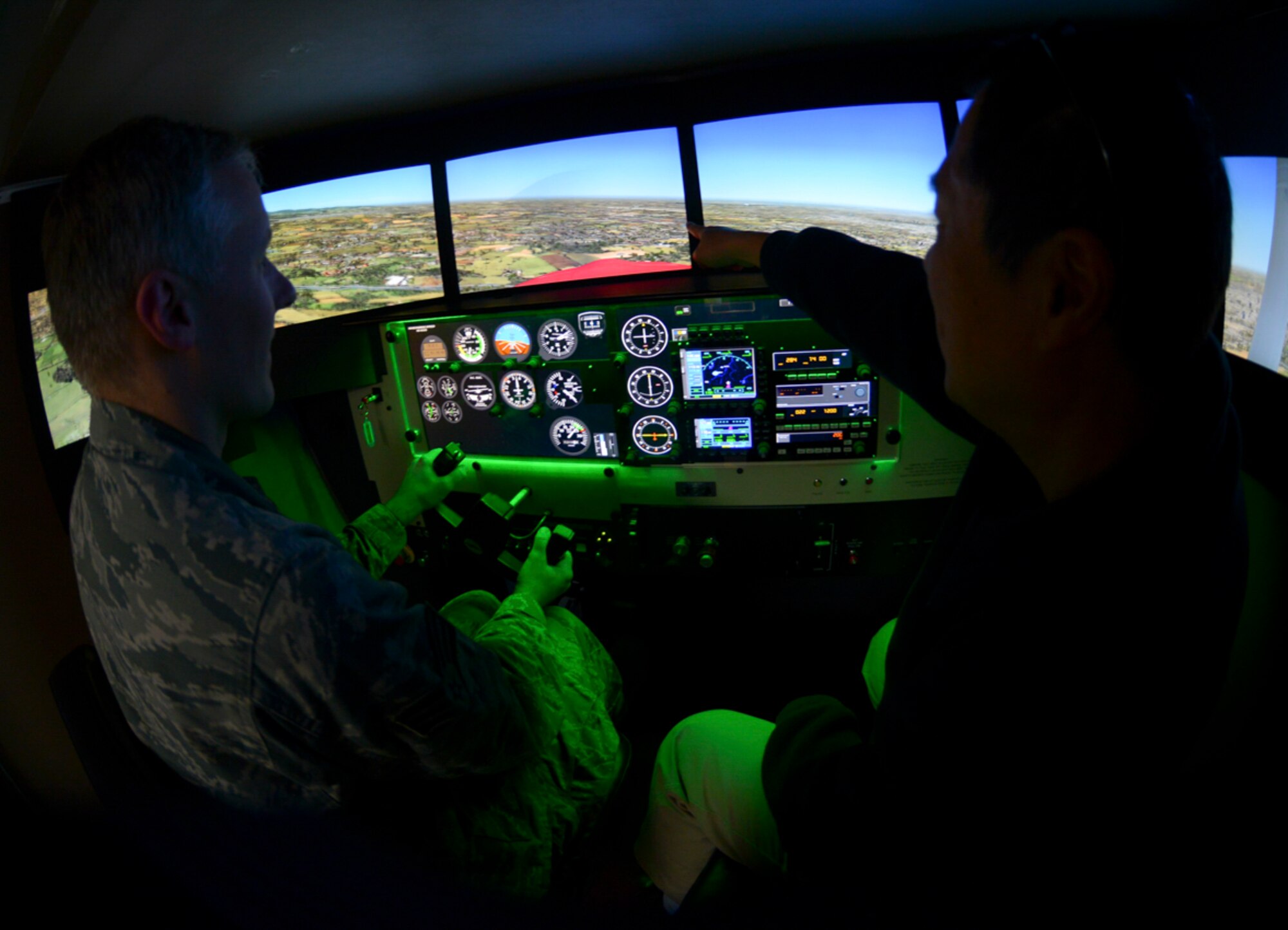 Masayoshi Nakano, Yokota Aero Club and Flight Training Center flight instructor, assists Senior Airman Justin Carnahan, 374th Airlift Wing Public Affairs broadcast journalist, inside the Redbird flight simulator at Yokota Air Base, Japan, Feb. 22, 2015. The flight simulator is designed to mimic the visuals, controls and movement of a Cessna. The aero club makes the simulator available to U.S. military personnel, Japanese citizens with Status of Forces Agreement status and escorted visitors for hourly rental. (U.S. Air Force photo by Airman 1st Class Elizabeth Baker/Released)