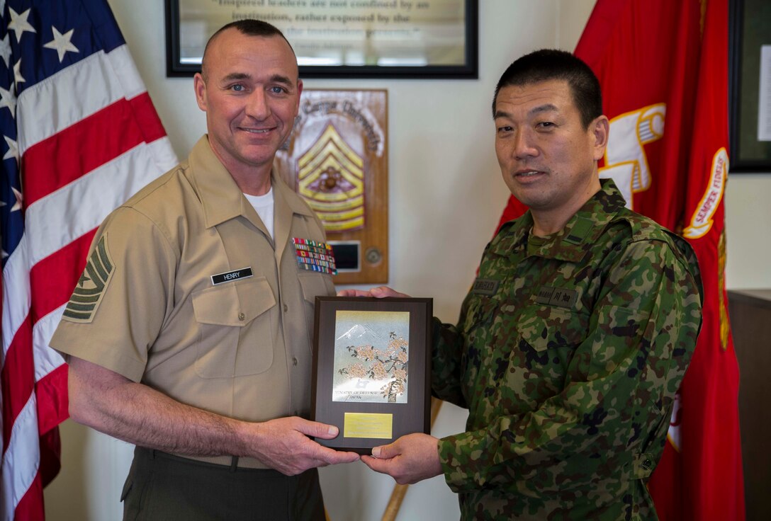 Japanese Ground Self-Defense Force Warrant Officer Hiromori Kawahata, right, poses for a photo with U.S. Marine Sgt. Maj. Jonathan Henry after the JGSDF toured the Staff Non-Commissioned Officer Academy (SNCOA) at Camp Hansen, Okinawa, Japan, March 4, 2016. The SNCOA hosted the JGSDF during a Japanese Observer Exchange Program event where JGSDF personnel observed the way the SNCOA teaches Marines leadership skills. The JGSDF observed presentations that explained U.S. Marine rank progression and the instruction each Marine receives as they progress throughout their career. The Japan Observer Exchange Program gives Marines and Sailors with the III Marine Expeditionary Force and members of the JSDF the opportunity to observe the training of their counterparts to increase mutual understanding and interoperability. Kawahata is the Sergeant Major for the JGSDF. Henry from Riddleton, Tennessee, is the director of the SNCOA. (U.S. Marine Corps Photo by Cpl. Devon Tindle/Released)