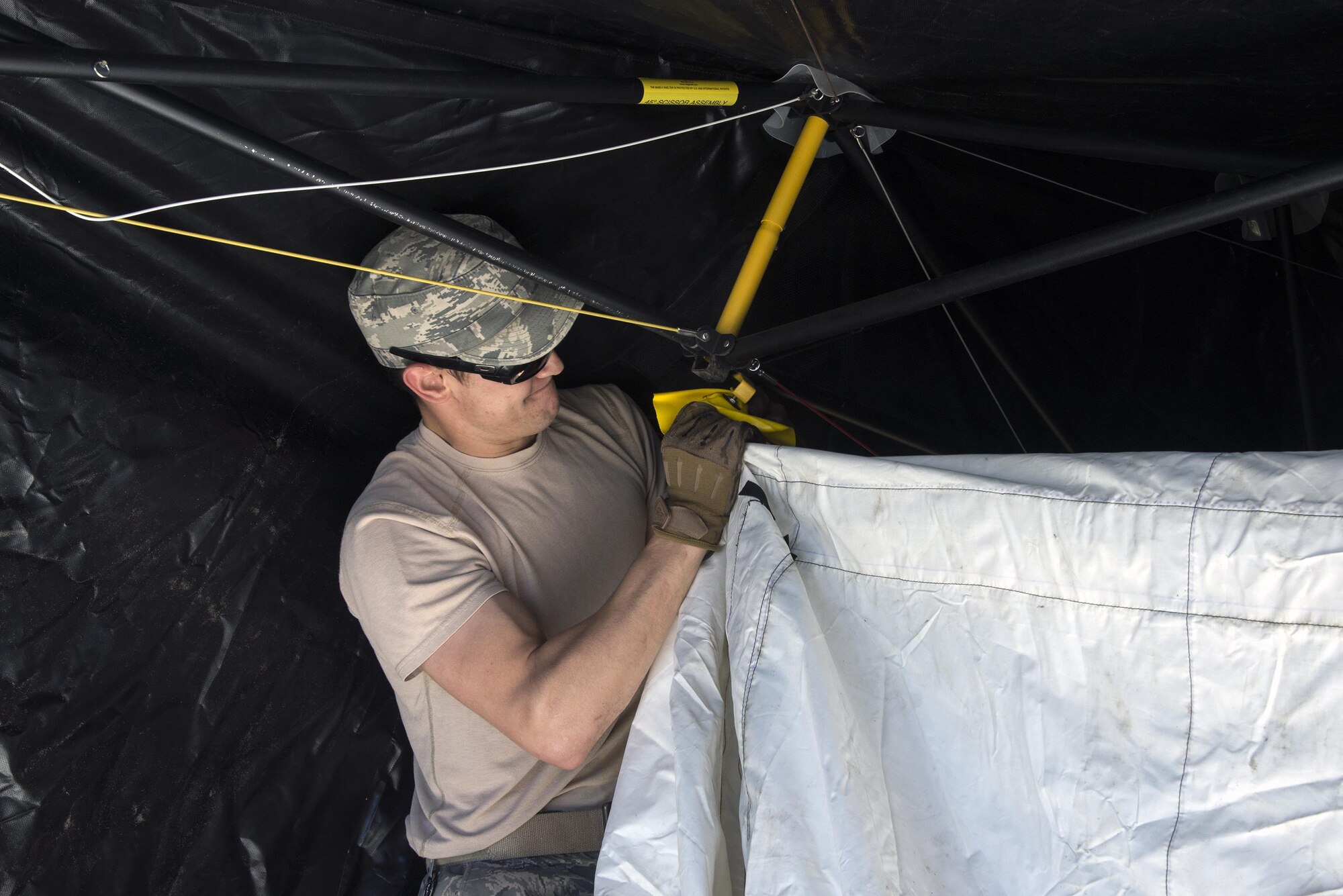 U.S. Air Force Senior Airman Daniel Simoes, 823d Base Defense Squadron unit trainer, secures the inner lining of a tent, March 2, 2016 at Moody Air Force Base, Ga. Airmen practiced setting up tents and generators in preparation for an upcoming Mission Readiness Exercise.
(U.S. Air Force photo by Airman 1st Class Janiqua P. Robinson/Released)
