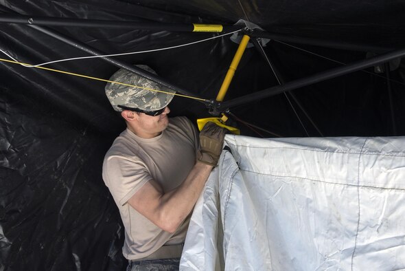 U.S. Air Force Senior Airman Daniel Simoes, 823d Base Defense Squadron unit trainer, secures the inner lining of a tent, March 2, 2016 at Moody Air Force Base, Ga. Airmen practiced setting up tents and generators in preparation for an upcoming Mission Readiness Exercise.
(U.S. Air Force photo by Airman 1st Class Janiqua P. Robinson/Released)
