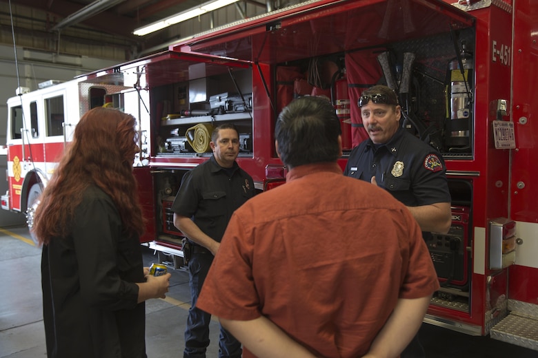 Anthony Marchisio and Wes Collins, fire inspection protectors, Combat Center Fire Department, show Twentynine Palms High School Students their firefighting equipment during the 13th annual Job Shadowing Event aboard the Combat Center Feb. 23, 2016. The event began as a partnership between the Morongo Unified School District and the installation and provides students with insight on potential careers. (Official Marine Corps photo by Lance Cpl. Levi Schultz/Released)