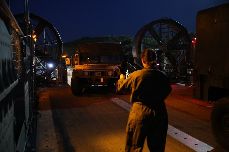 A crew member aboard a Landing Craft Air Cushion directs a High Mobility Multipurpose Wheeled Vehicle driver into position at Camp Pendleton Feb. 22, 2016. The vehicles were transported to the USS Essex (LHD 2) to start the Marine Corps Combat Readiness Evaluation of Company A, 3rd Assault Amphibian Battalion, 1st Marine Division.  The LCAC crew is with Assault Craft Unit 5. (U.S. Marine Corps photo by Lance Cpl. Timothy Valero/Released)