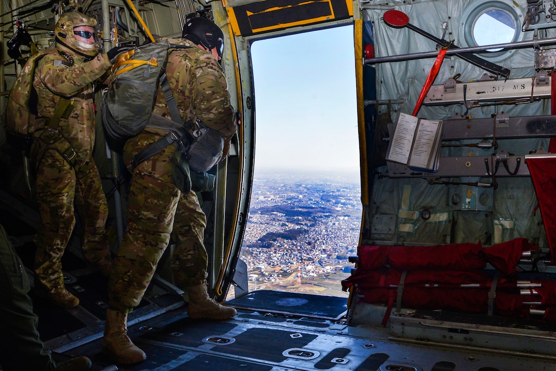 Air Force Staff Sgt. Justin Bender, right, prepares to jump out of a C-130 Hercules aircraft while flying over Yokota Air Base, Japan, March 2, 2016. Bender is a survival, evasion, resistance and escape trainer assigned to the 374th Operations Support Squadron. Air Force photo by Senior Airman David Owsianka