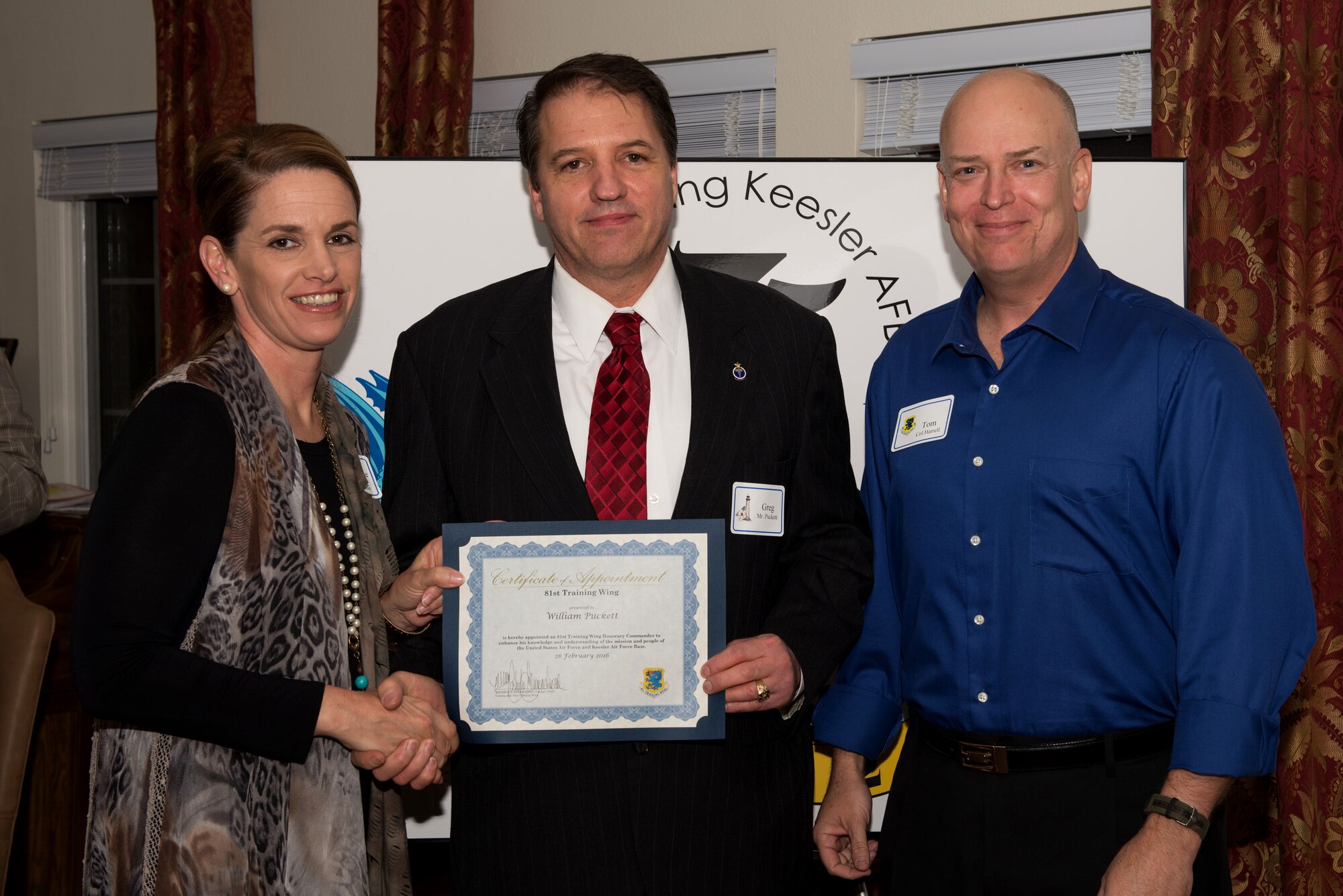 Col. Michele Edmondson, 81st Training Wing commander, presents a certificate to William Puckett and Col. Thomas Harrell, 81st Medical Group commander, during the honorary commander reception and induction ceremony Feb. 26, 2016, Keesler Air Force Base, Miss. Each of the newly appointed honorary commanders received a certificate. (U.S. Air Force photo by Marie Floyd)