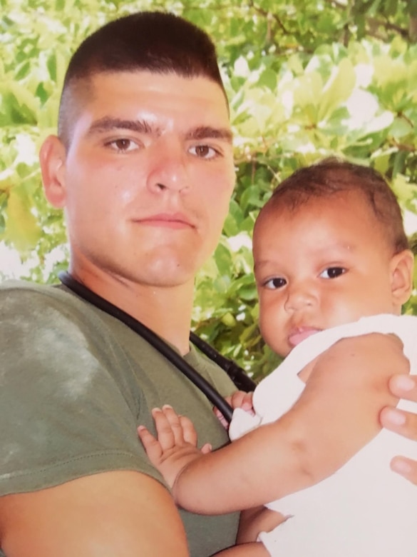 HM1(FMF) Manuel Reyes, medical group chief with Headquarters Squadron, Marine Aircraft Group 49, 4th Marine Aircraft Group, Marine Forces Reserve, poses for a picture with an infant patient during a humanitarian deployment to Honduras in 2006. Reyes is the active component recipient of the 2015 Marine Forces Reserve Sailor of the Year award. [Courtesy photo by HM1(FMF) Manuel Reyes]