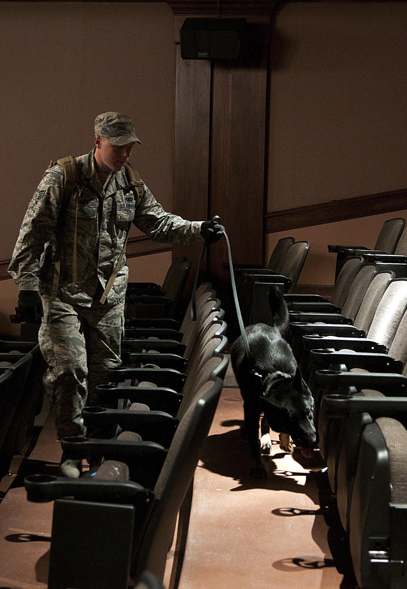 Senior Airman Kyle Snape, 790th Missile Security Forces Squadron member, leads Igo, 90th Missile Wing working dog, through the aisles of the base theater on F.E. Warren Air Force Base, Wyo., Feb. 29, 2016. Several teams coordinated their efforts to secure the facility and eliminate the opposing forces, played by volunteers. (U.S. Air Force photo by Airman 1st Class Malcolm Mayfield)