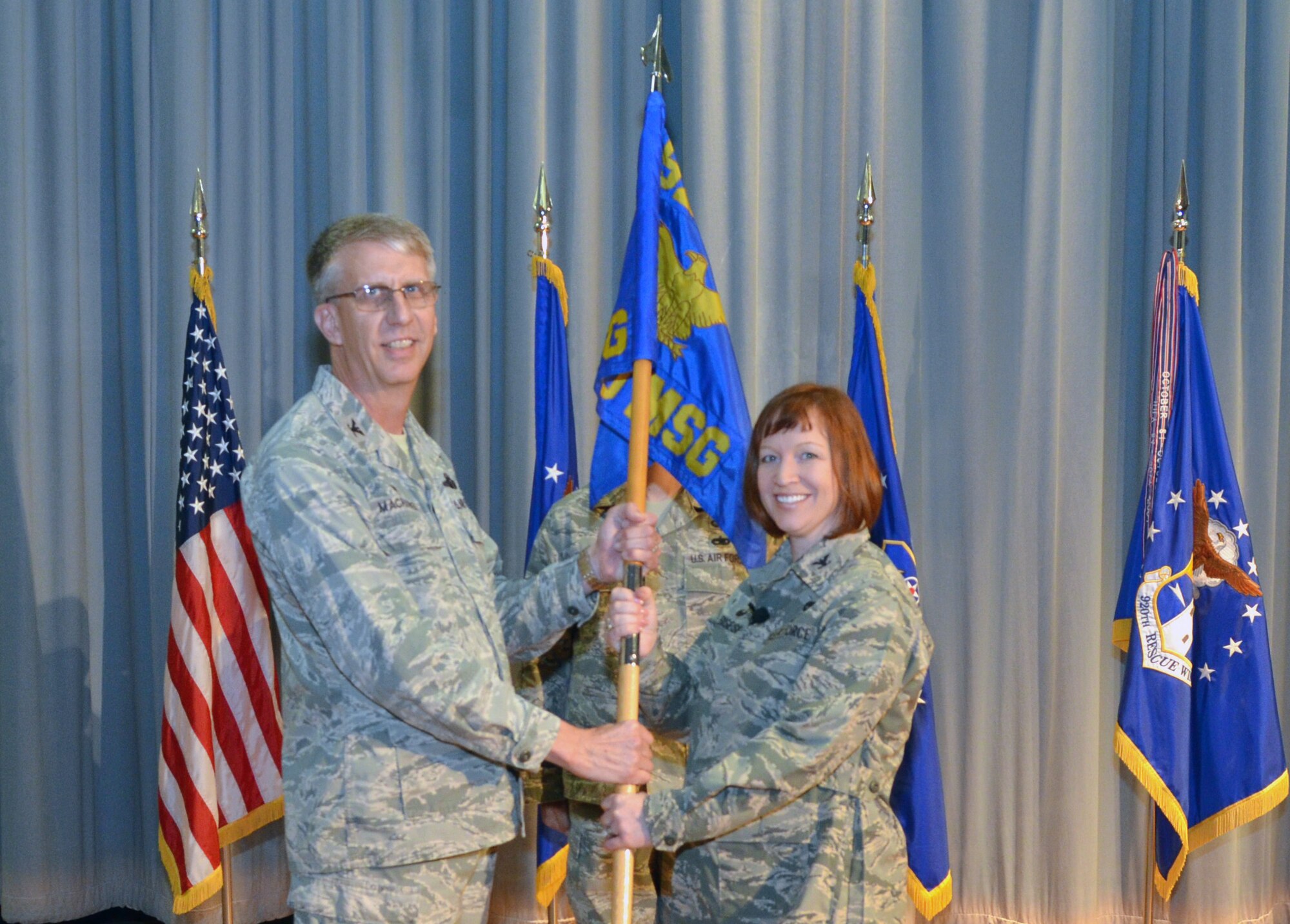 Col. Jeffrey Macrander, 920th Rescue Wing commander, hands the 920th Mission Support Group flag to Col. Jeanne Bisesi, new 920th MSG commander, during an assumption of command ceremony at Patrick Air Force Base March 3, 2016. The traditional passing of the flag symbolizes the formal passing of responsibility, authority and accountability of command. (U.S. Air Force photo by 2nd Lt. Anna-Marie Wyant)