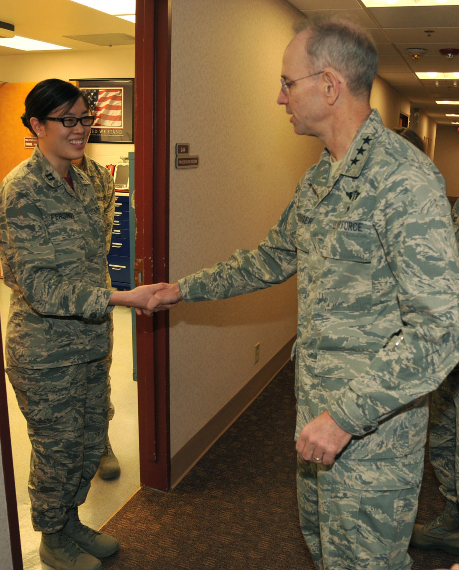 Air Force Surgeon General Lt. Gen. (Dr.) Mark Ediger, right, presents Capt. Christine Persinger, 319th Medical Operations Squadron family health physician, with a coin for her contributions to the 319th Medical Group March 4, 2016, on Grand Forks Air Force Base, North Dakota. Gen. Ediger visited with many Airmen during his tour of the medical facilities. (U.S. Air Force photo by Airman 1st Class Ryan Sparks/Released)