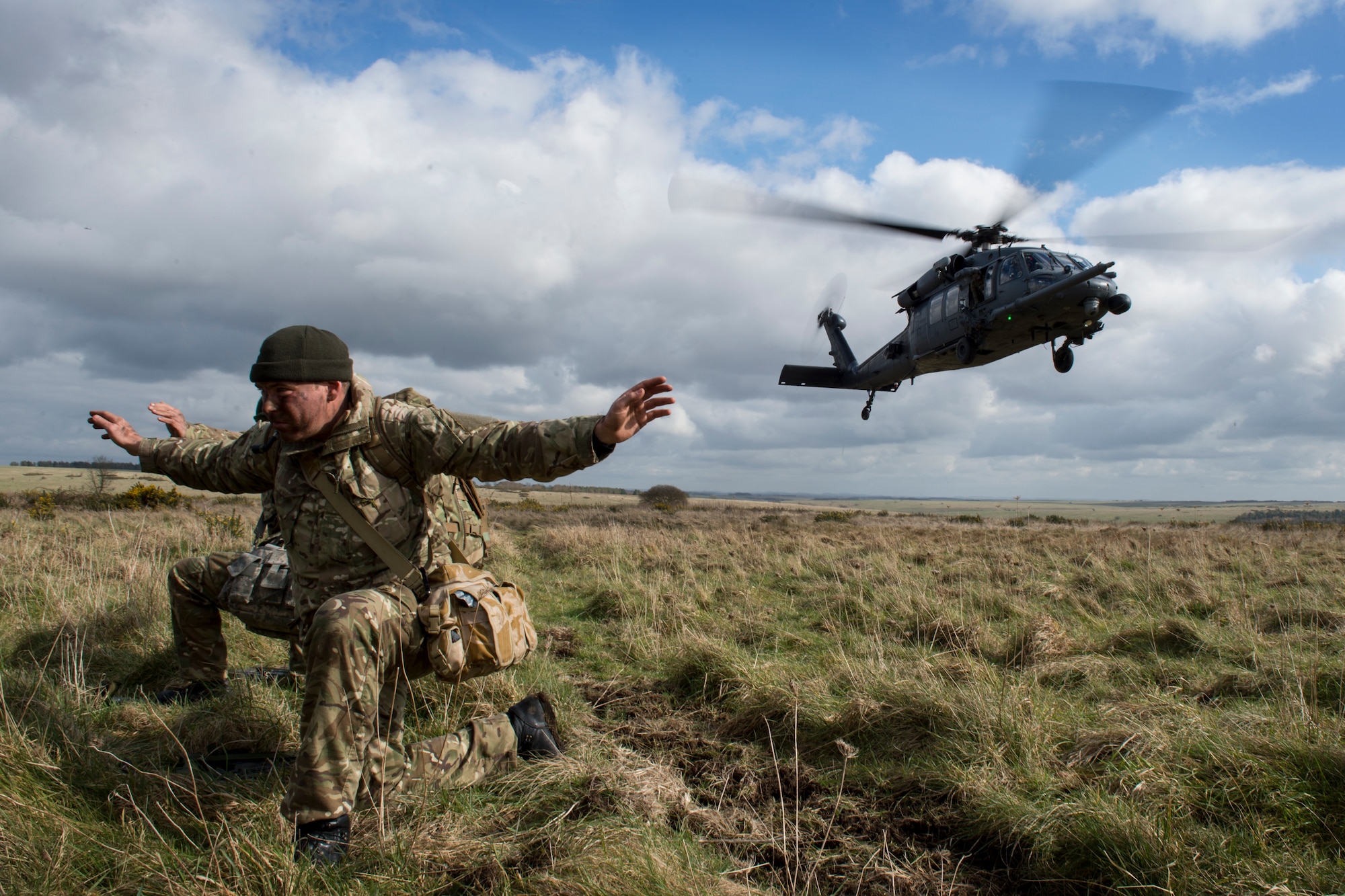 Two British Army AH-64 Apache pilots from 663 Squadron, 3 Regiment Army Air Corps, wait to be extracted from the field by an HH-60G Pave Hawk during a rescue scenario as part of exercise Voijek Valour at Salisbury Plain, England, March 3, 2016. The exercise helped strengthen relationships established when U.S. and U.K. military forces worked together in Afghanistan. (U.S. Air Force photo/Airman 1st Class Erin R. Babis)