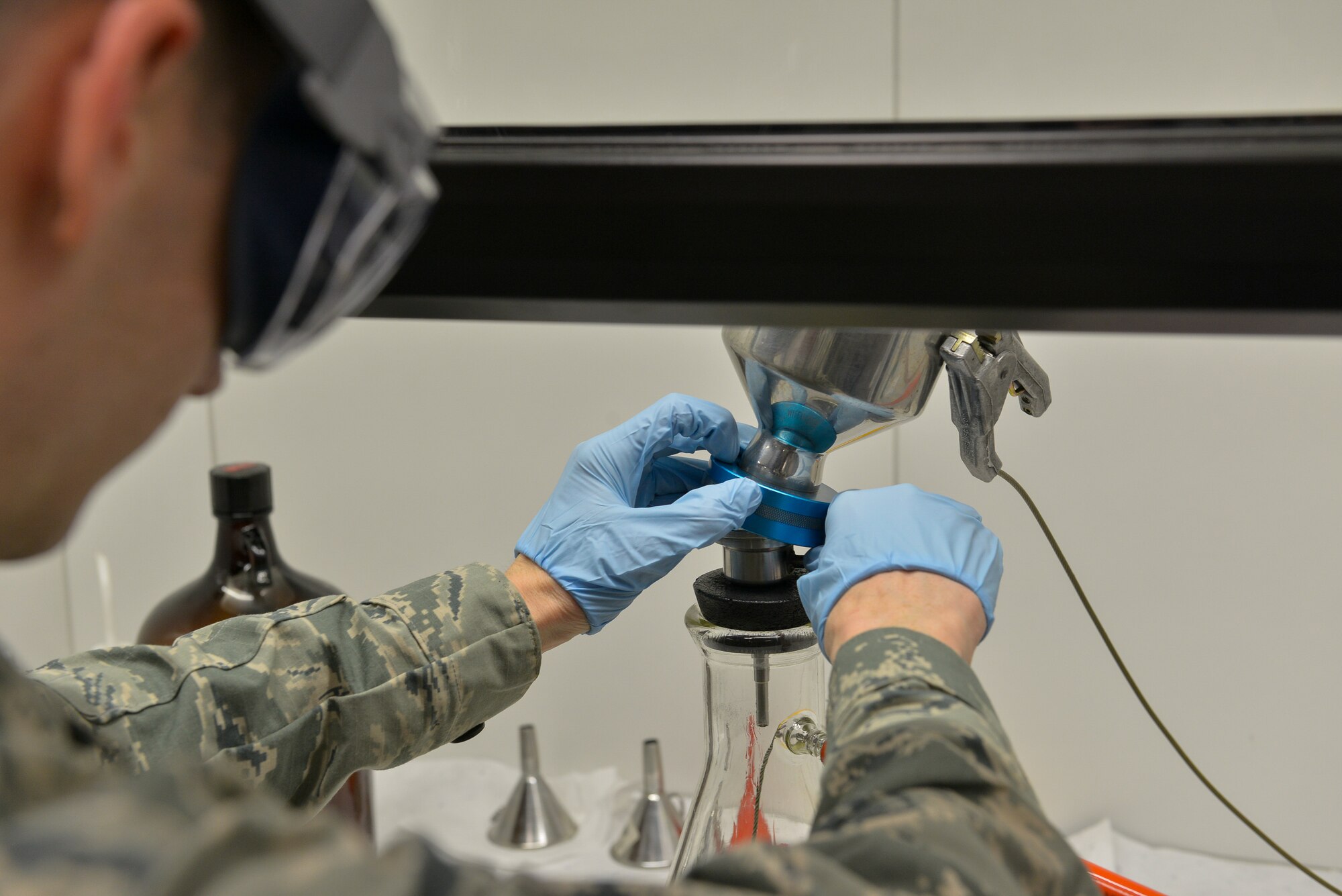 Senior Airmen Matthew Jameson, 86th Logistics Readiness Squadron fuels laboratory technician, removes the filtering funnel from the beaker, after pouring fuel into it, to find the particles filtered out during a fuel sample test Mar. 3, 2016, at Ramstein Air Base, Germany. Removing particles from fuel samples is vital to mission success, as these specks can cause engine disruption for planes and vehicles. (U.S. Air Force photo/Airman 1st Class Lane T. Plummer)