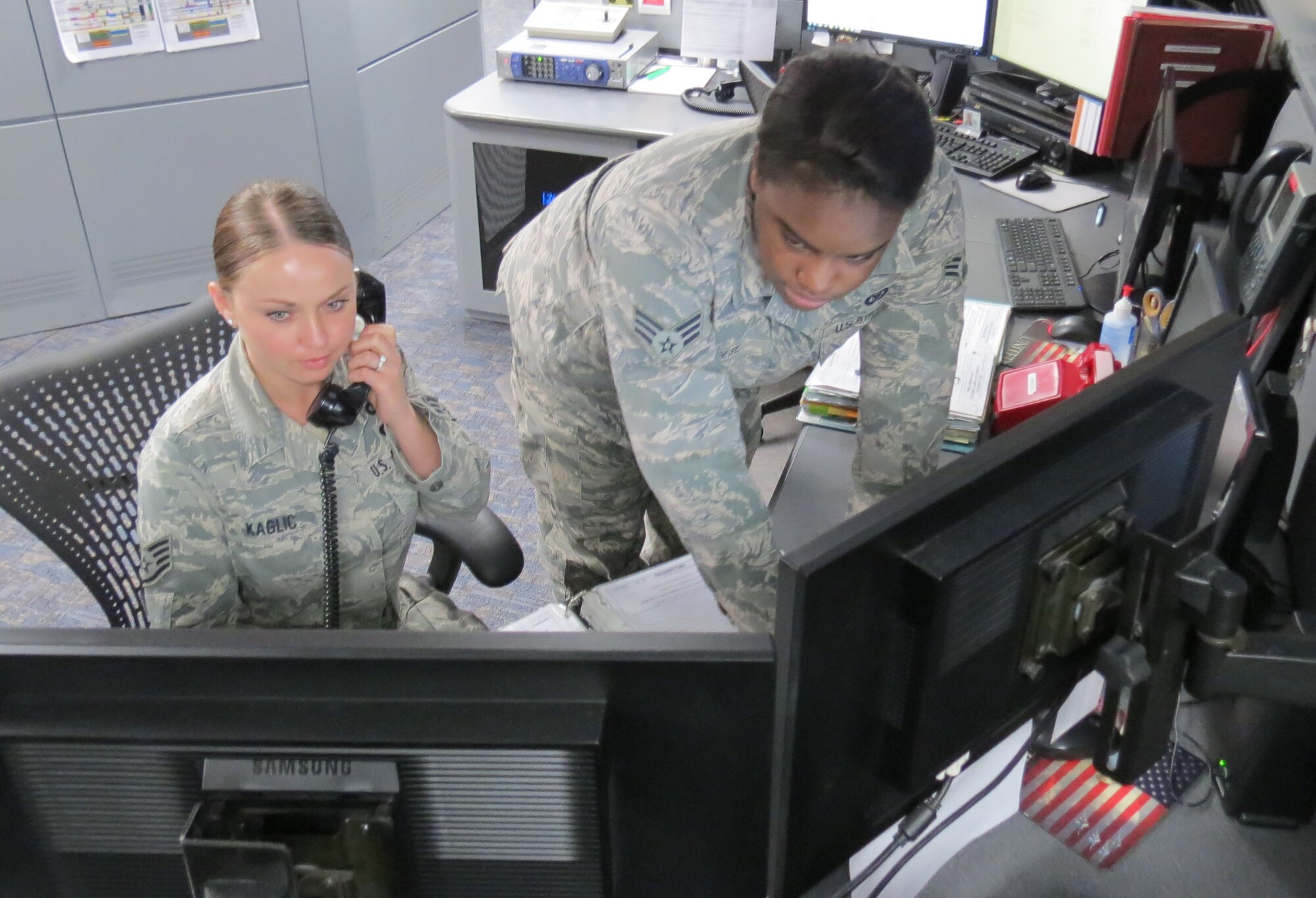 Tinker Air Force Base Command Post Controllers Staff Sgt. Lara Kaglic, left, and Senior Airman Ahna Reese check on a recent situation inside the base’s secure communications facility. Base personnel with Air Force network access are encouraged to update their AtHoc emergency notification information and download the AtHoc Notifier app. (Courtesy photo)