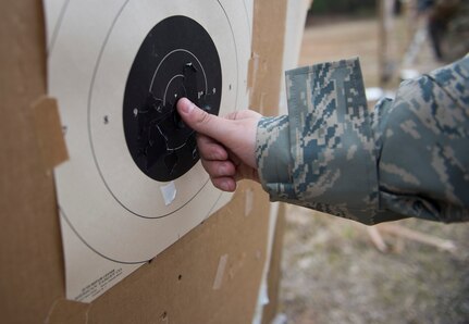 A combat camera Airman covers the holes on a paper target March 3, 2016, during exercise Scorpion Lens 2016, at McCrady Training Center, Fort Jackson, South Carolina. The exercise is an annual training requirement incorporating combat camera job qualification standards and advanced weapons and tactical training with Army instructors. (U.S. Air Force photo/Staff Sgt. Jared Trimarchi)