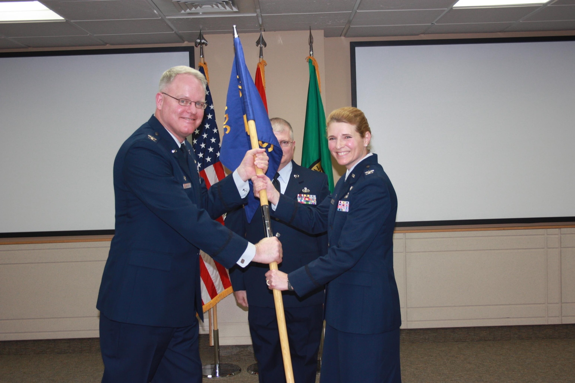 Col. William Krueger, 225th Air Defense Group commander, hands off the guidon to Col. Paige Abbott, 225th Support Squadron commander, during the 225th Support Squadron change of command at the Western Air Defense Sector on Joint Base Lewis-McChord, Wash., Jan. 29, 2016. The 225th Support Squadron is a subordinate unit of the 225th Air Defense Group, which conducts the Western Air Defense Sector's (WADS) mission. WADS is responsible for air sovereignty and counter-air operations over the western United States and directs a variety of assets to defend 2.2 million square miles of land and sea. (U.S. Air National Guard photo by 1st Lt. Colette Muller/Released)